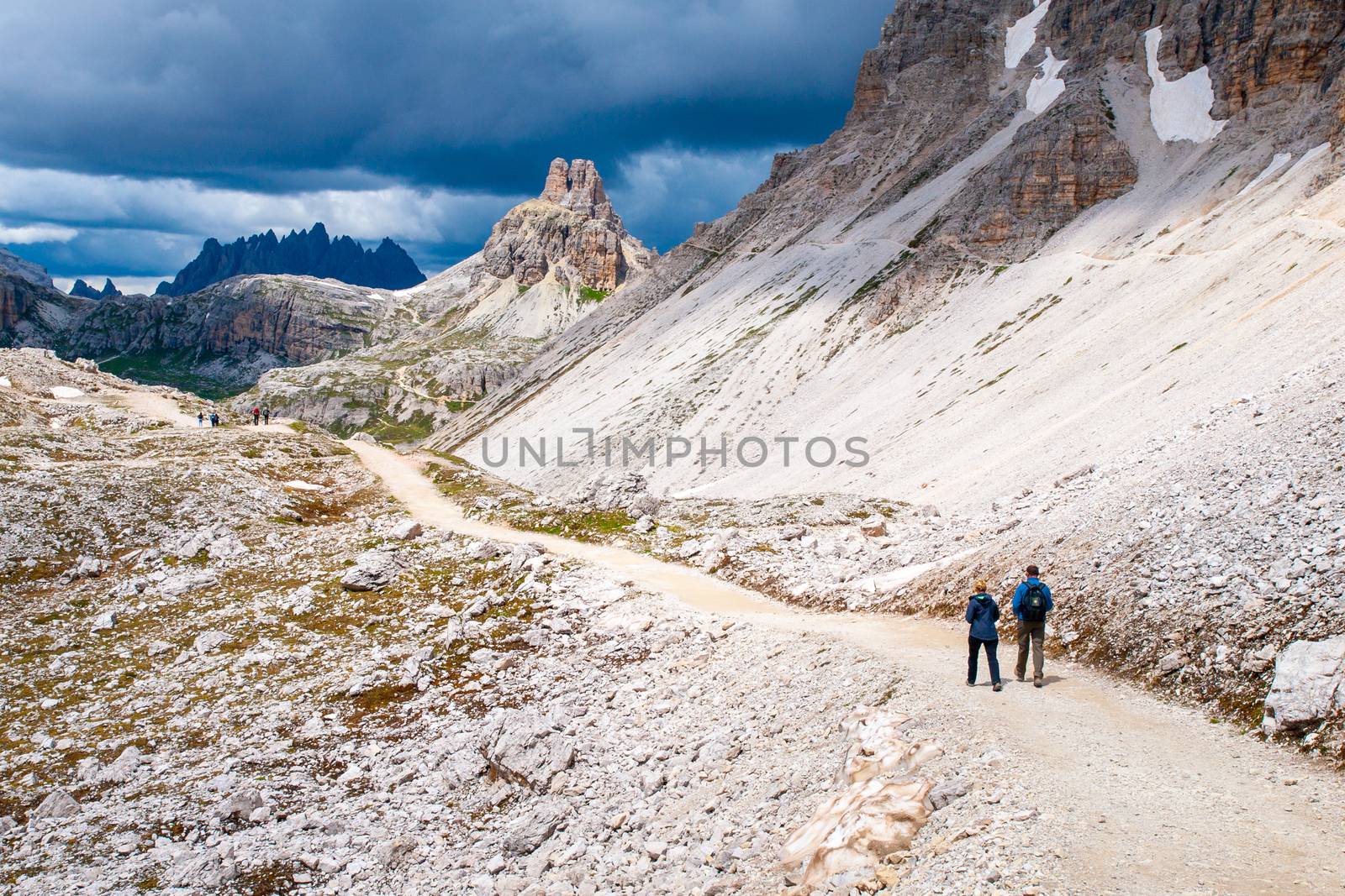 Mountain hikers with trekking poles walks on the rocky path in the mountains. Nordic walking theme by pyty