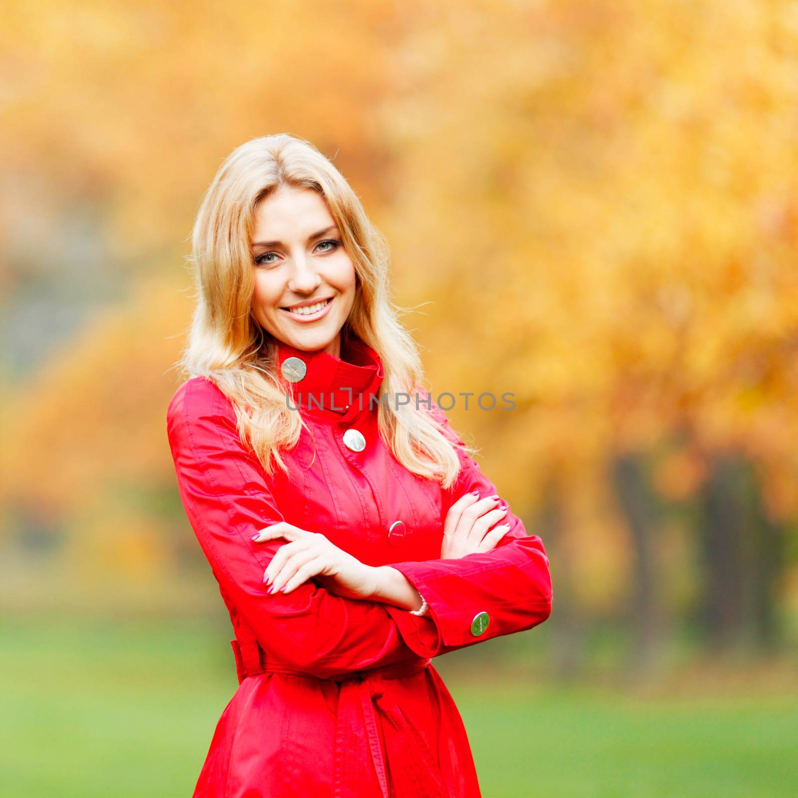 Young woman in red coat walking in autumn park