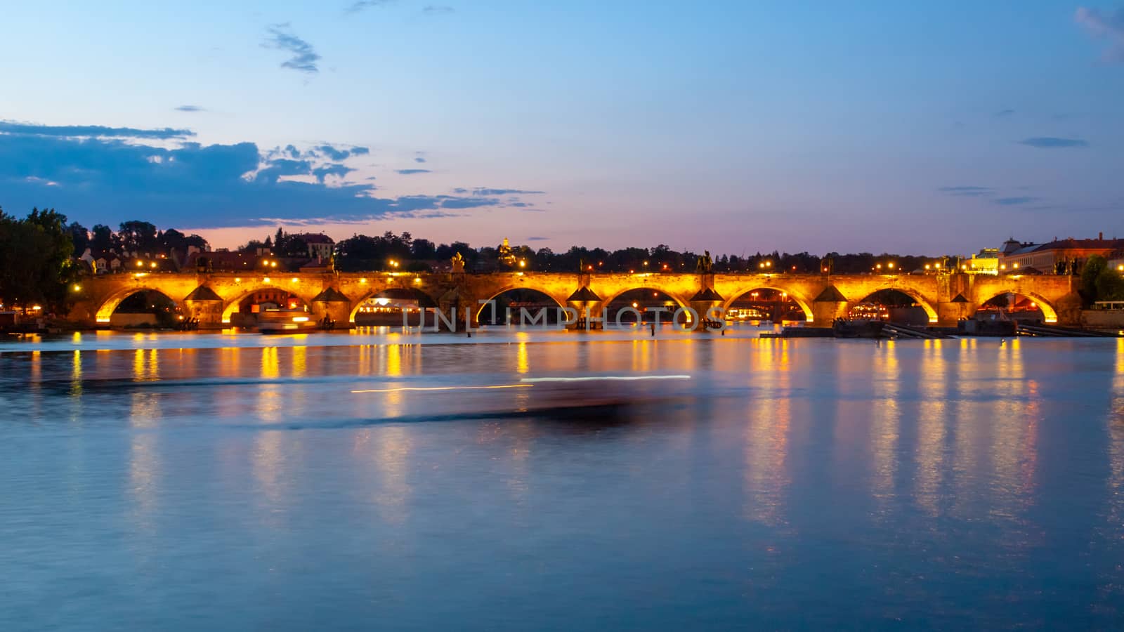 Illuminated Charles Bridge reflected in Vltava River by night. Prague, Czech Republic by pyty