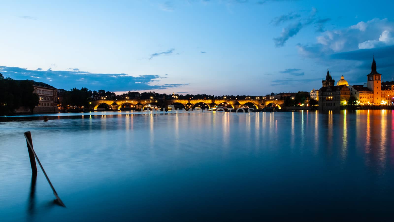 Illuminated Charles Bridge reflected in Vltava River by night. Prague, Czech Republic by pyty