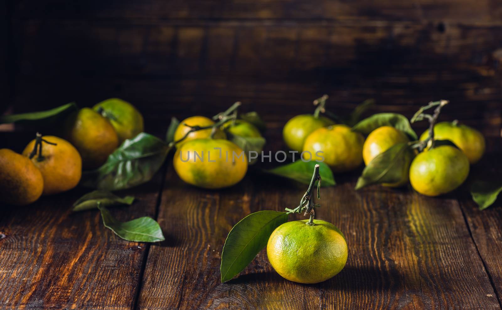 Ripe Tangerines with Leaves Lie on Wooden Surface