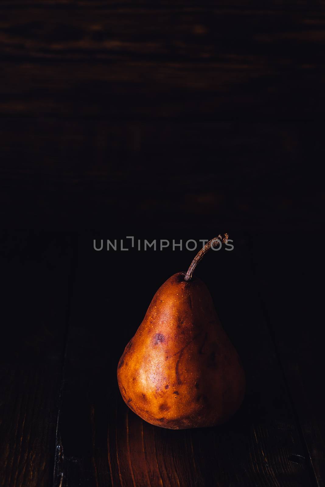 One Golden Pear on Dark Background. Vertical Photo with Copy Space