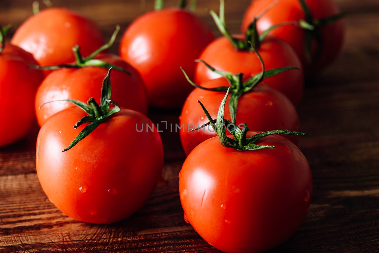 Ripe and Red Tomatoes with Water Drops Lie on Wooden Table