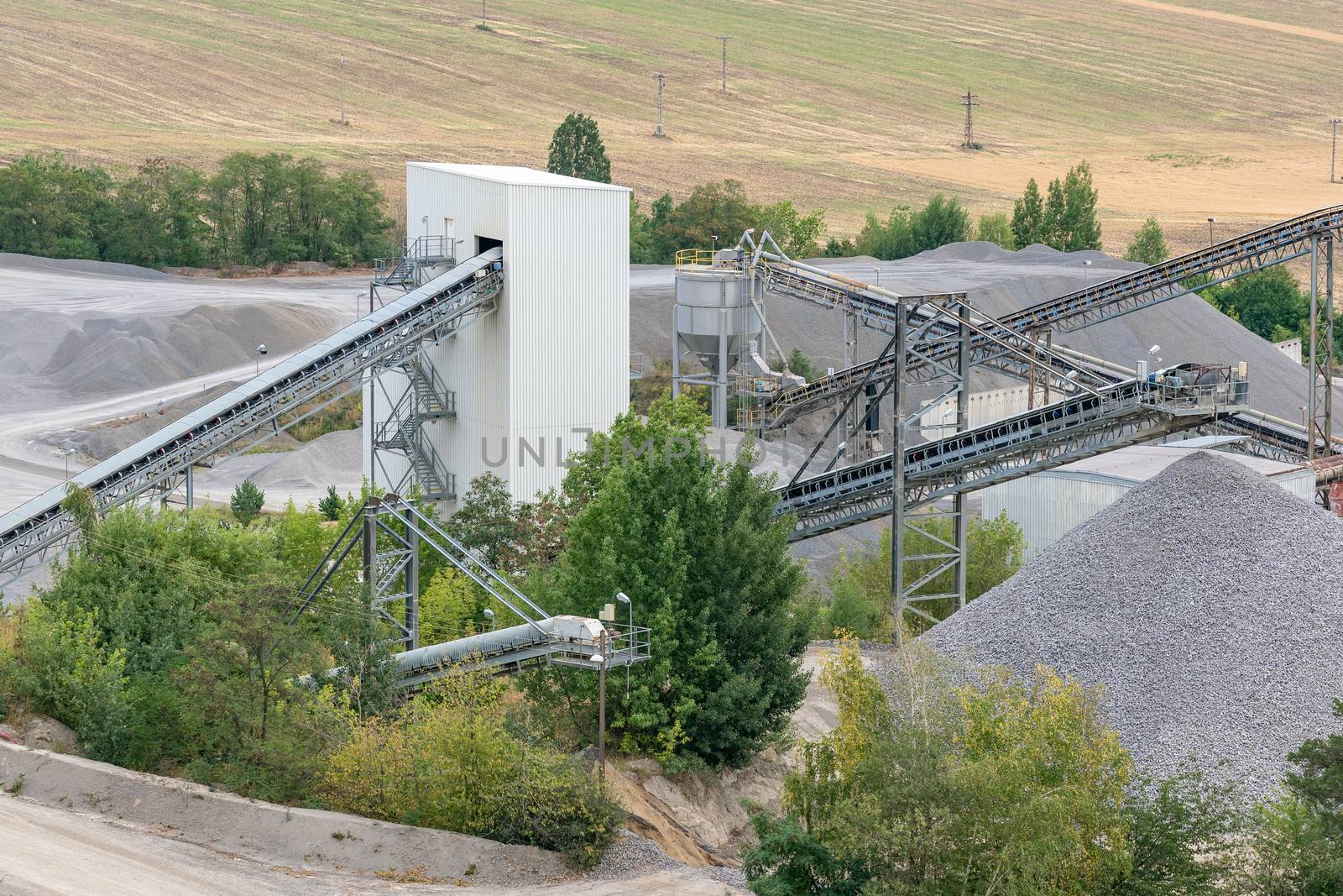 Mining quarry with machinery. Belt conveyors and mining equipment in a quarry.
Stone quarry with silos, conveyor belts and piles of stones. Quarrying of stones for construction works.