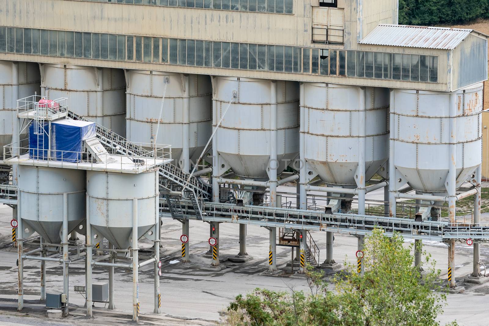 Big silos, belt conveyors and mining equipment in a quarry. Quarrying of stones for construction works. Mining industry in quarry.