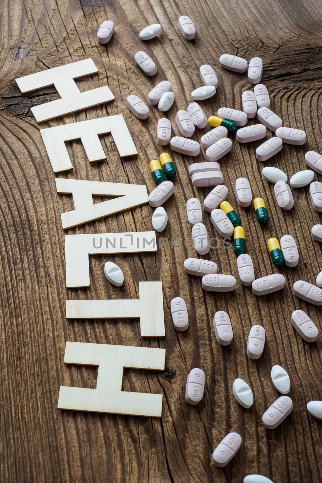 Pills with inscription Health on brown wooden surface background
