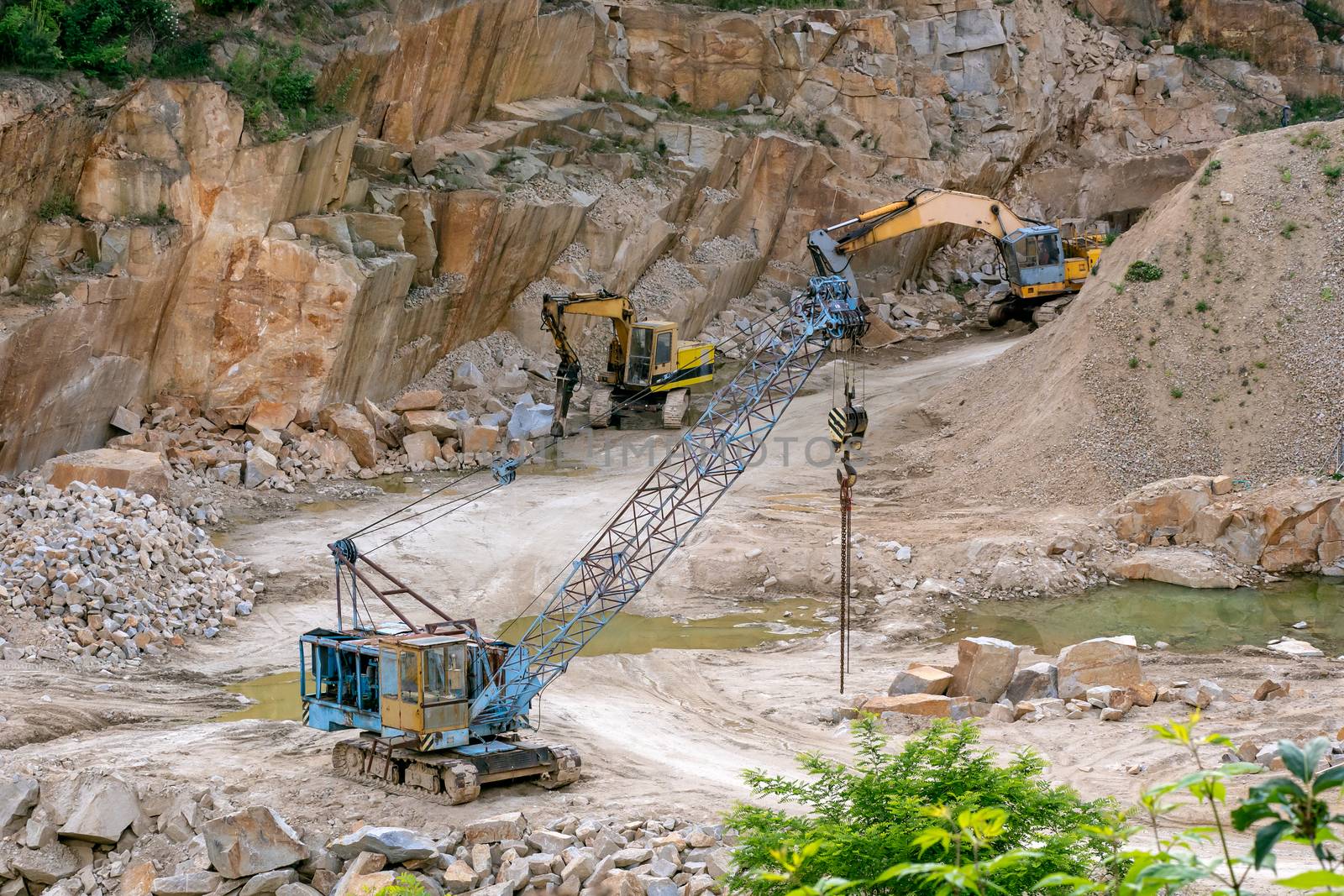 Mining in the granite quarry. Working mining machine - old crane and digger. Mining industry.