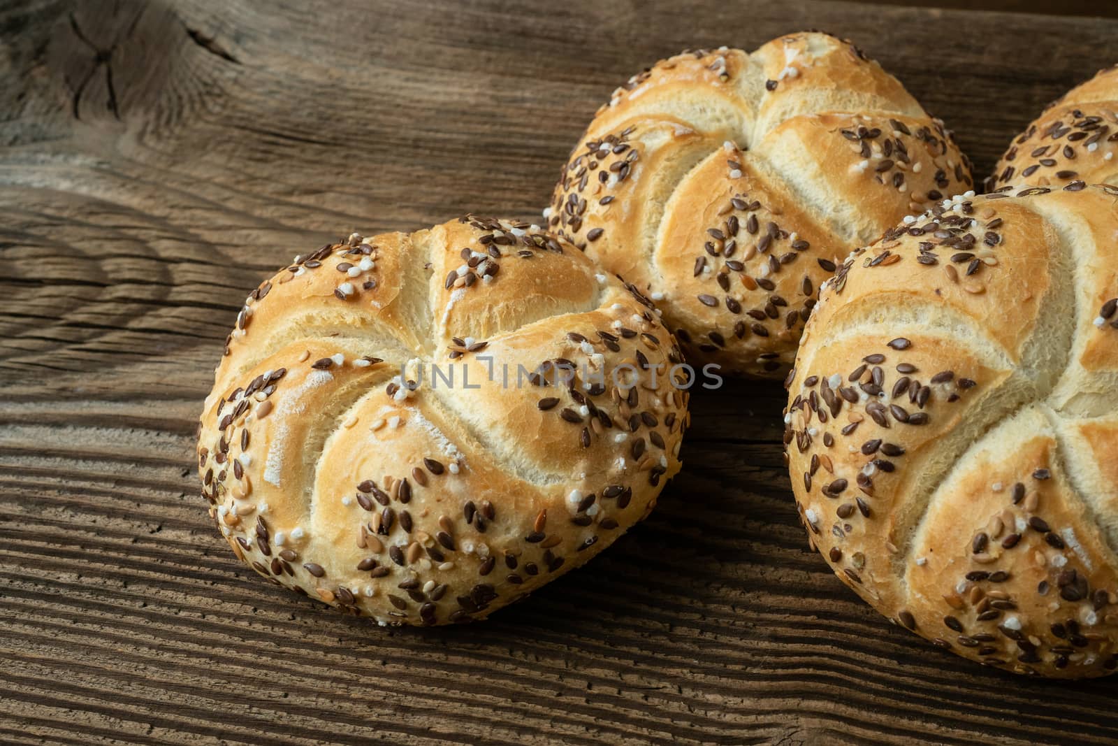 Whole wheat bread on wooden background. Bunch of kaiser rolls wi by xtrekx