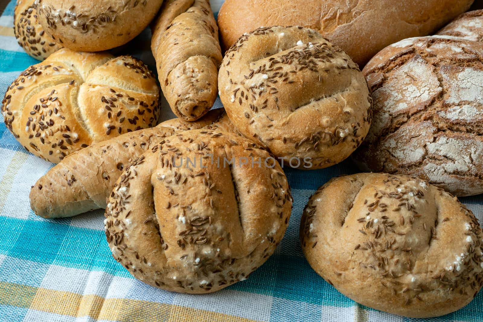 Heap of various bread rolls sprinkled with salt, caraway and ses by xtrekx