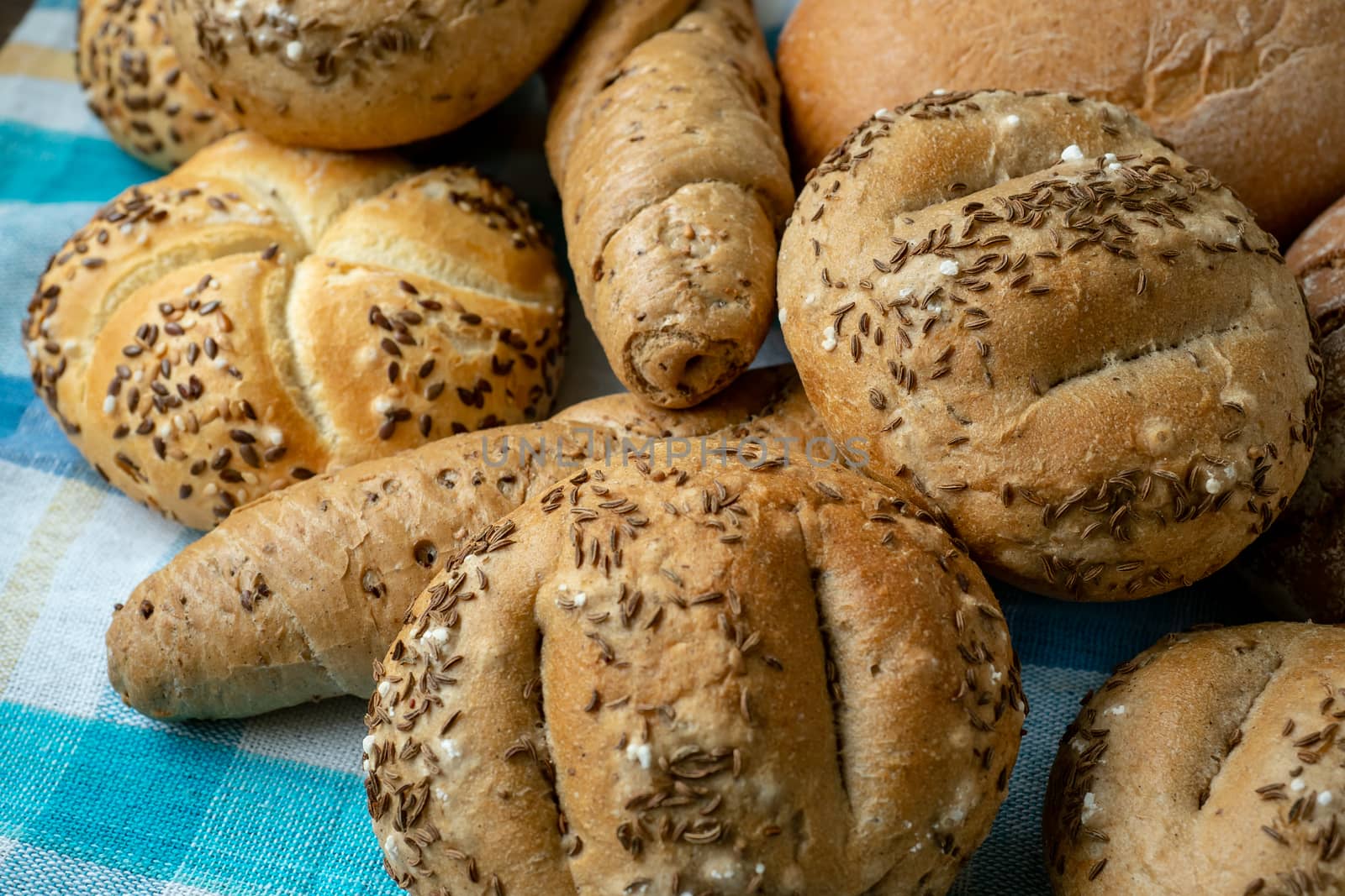 Heap of various bread rolls sprinkled with salt, caraway and sesame. Fresh rustic bread from leavened dough. Assortment of freshly of bakery products