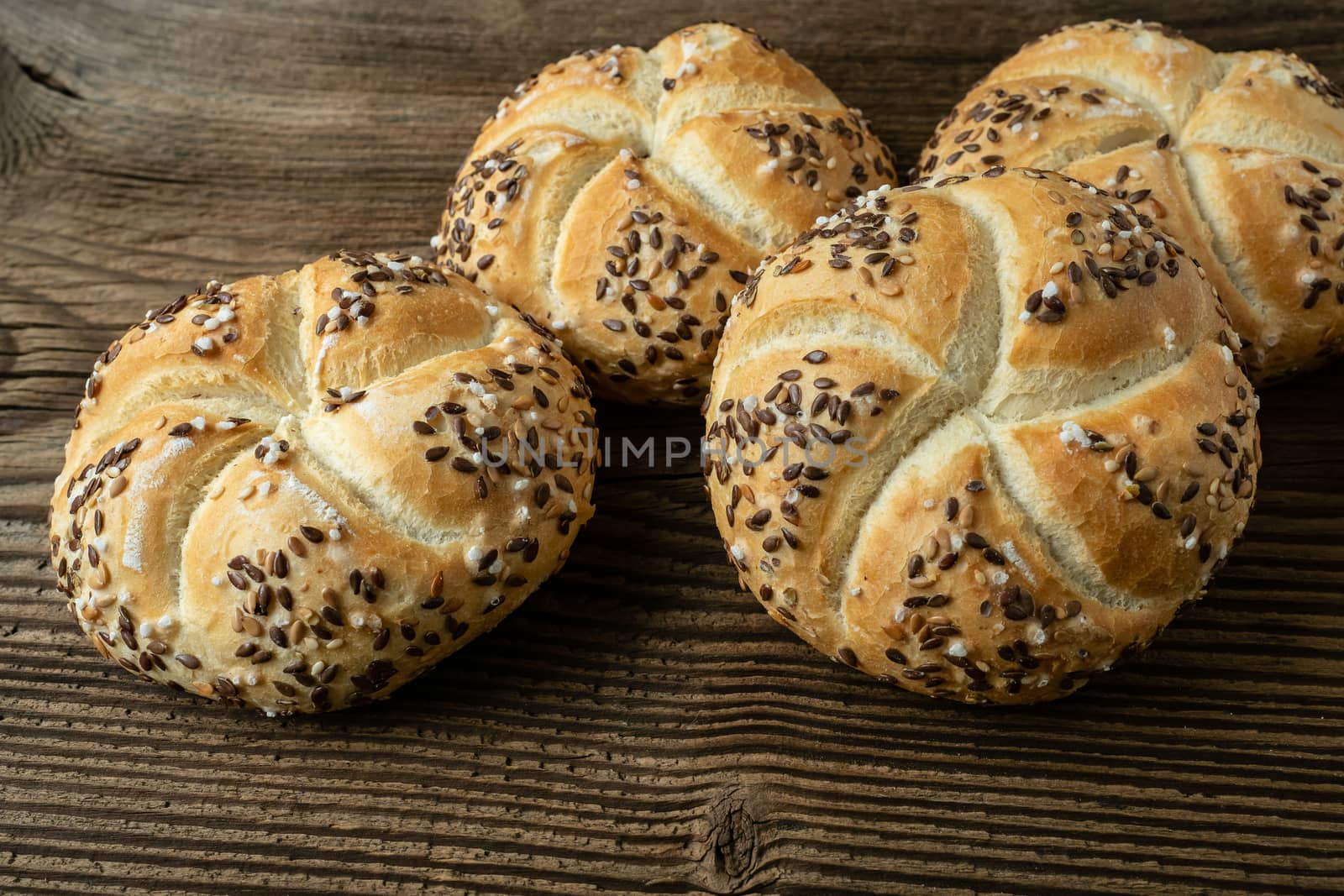 Whole wheat bread on wooden background. Bunch of kaiser rolls with sesame.