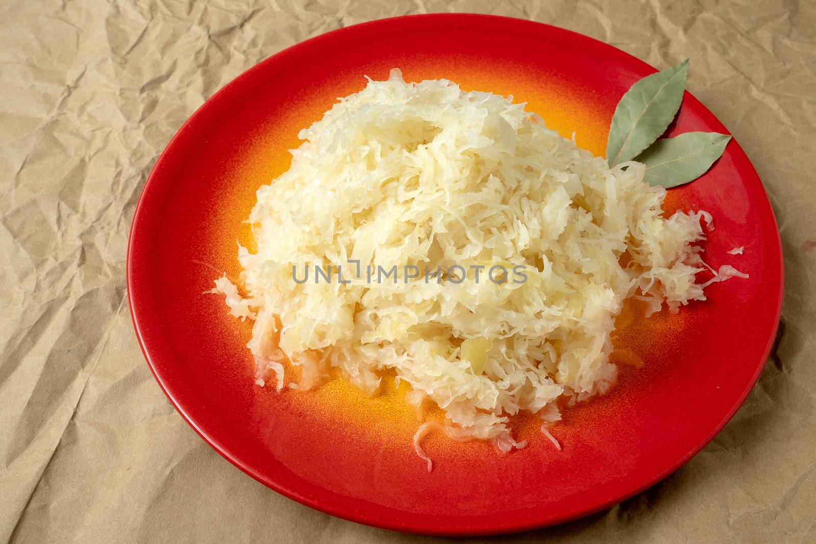 Fermented cabbage. Red plate of sauerkraut (pickled white cabbage).