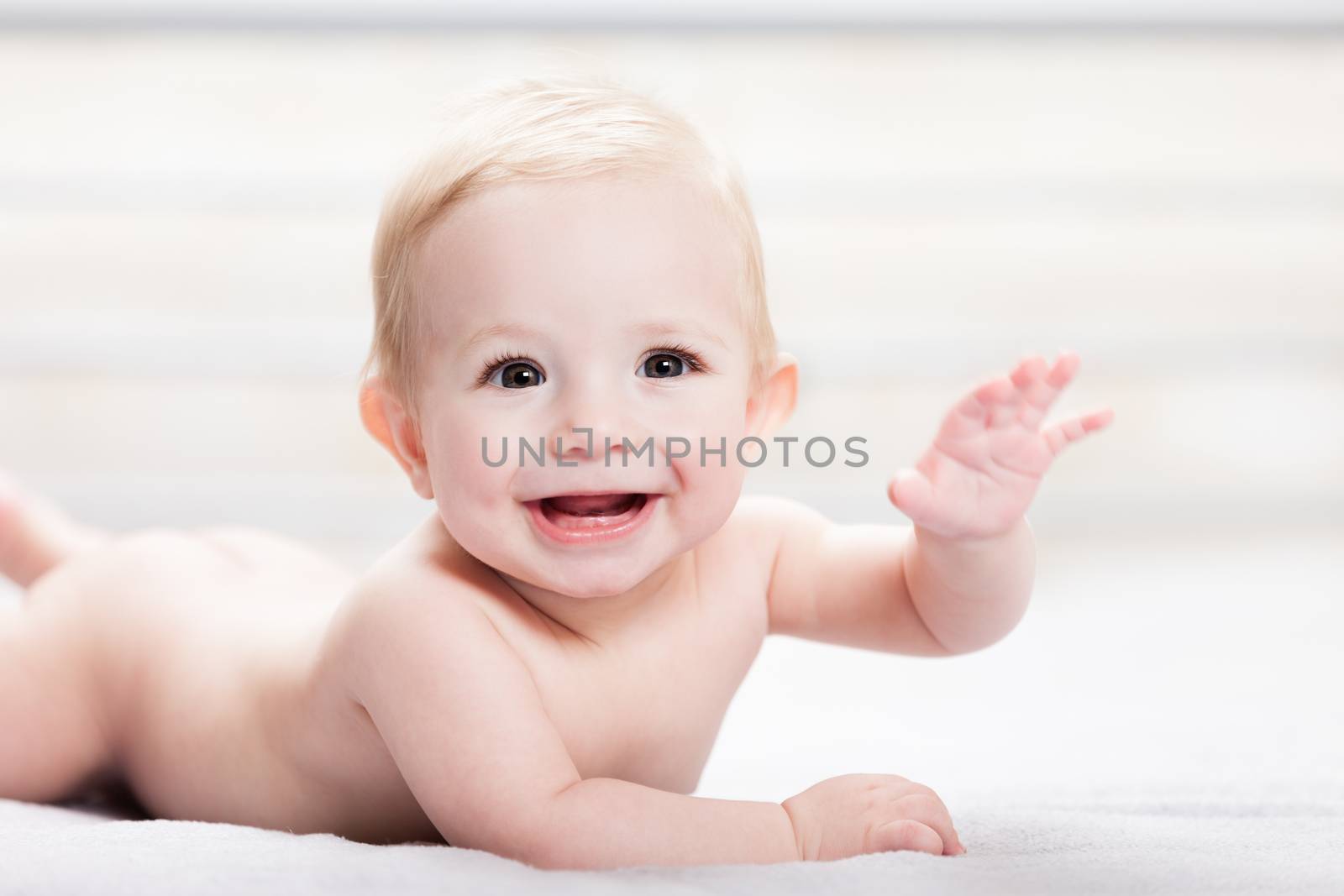 Little cute smiling newborn baby child boy hand gesturing hello or goodbye sign