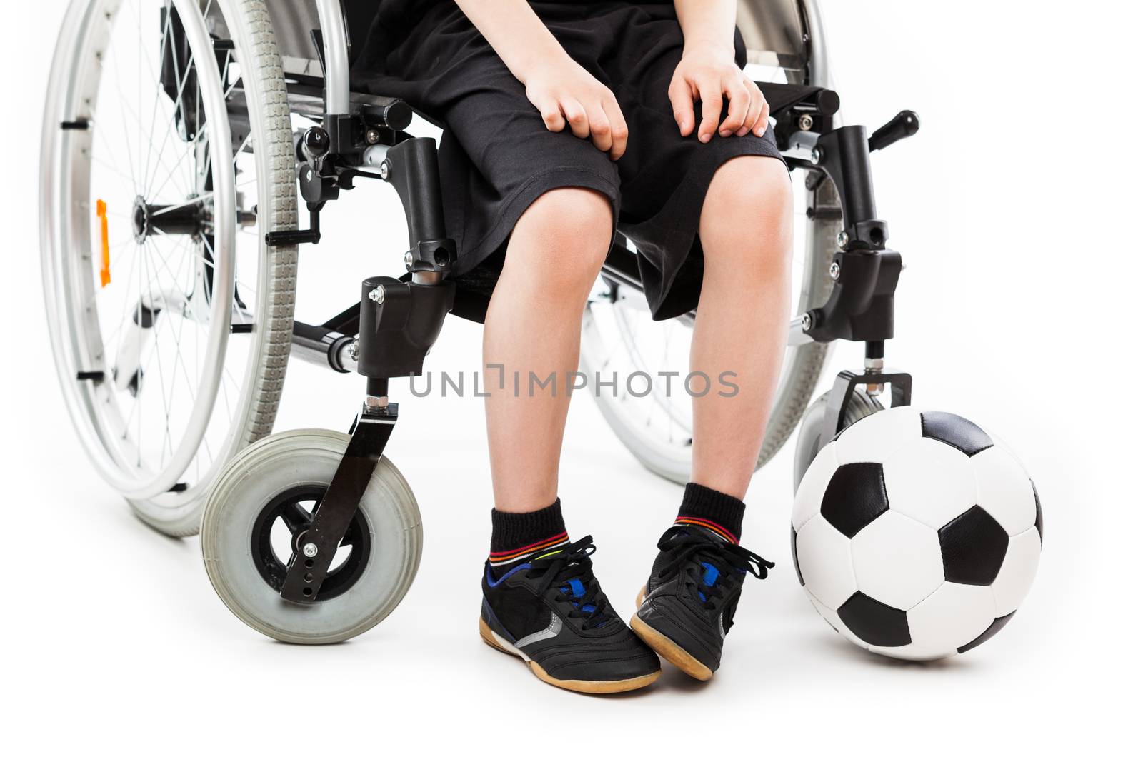 Disabled child boy sitting on wheelchair holding soccer ball by ia_64