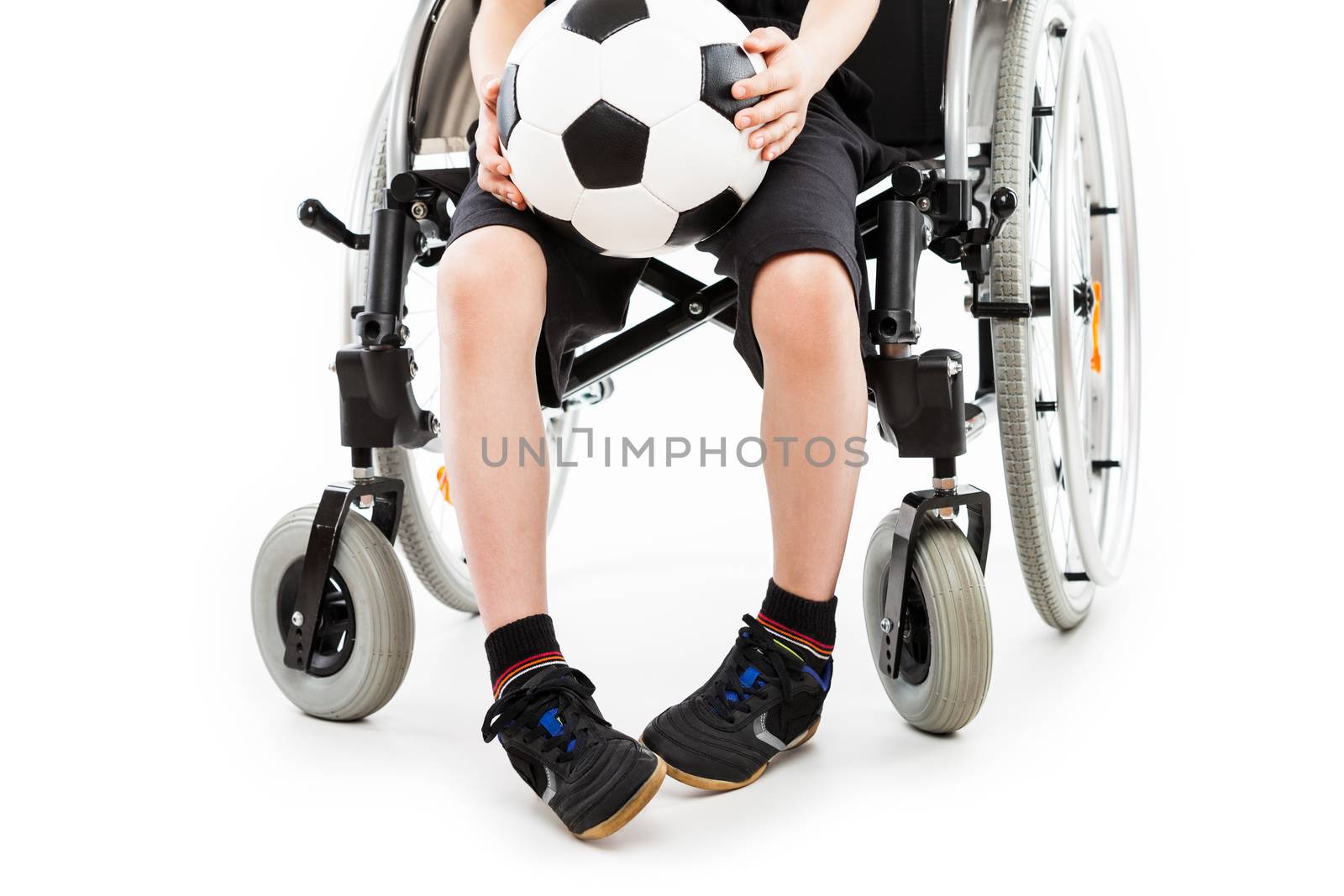 Invalid or disabled child boy sitting on wheelchair hand holding soccer sport ball white isolated