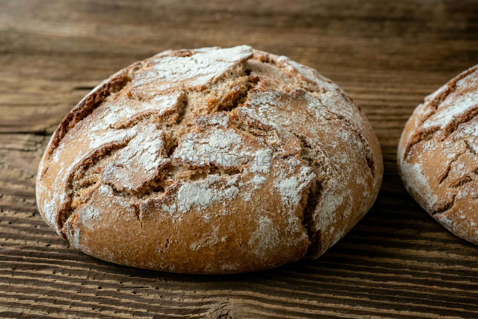 A freshly baked rustic, loaf of bread on an old wooden table