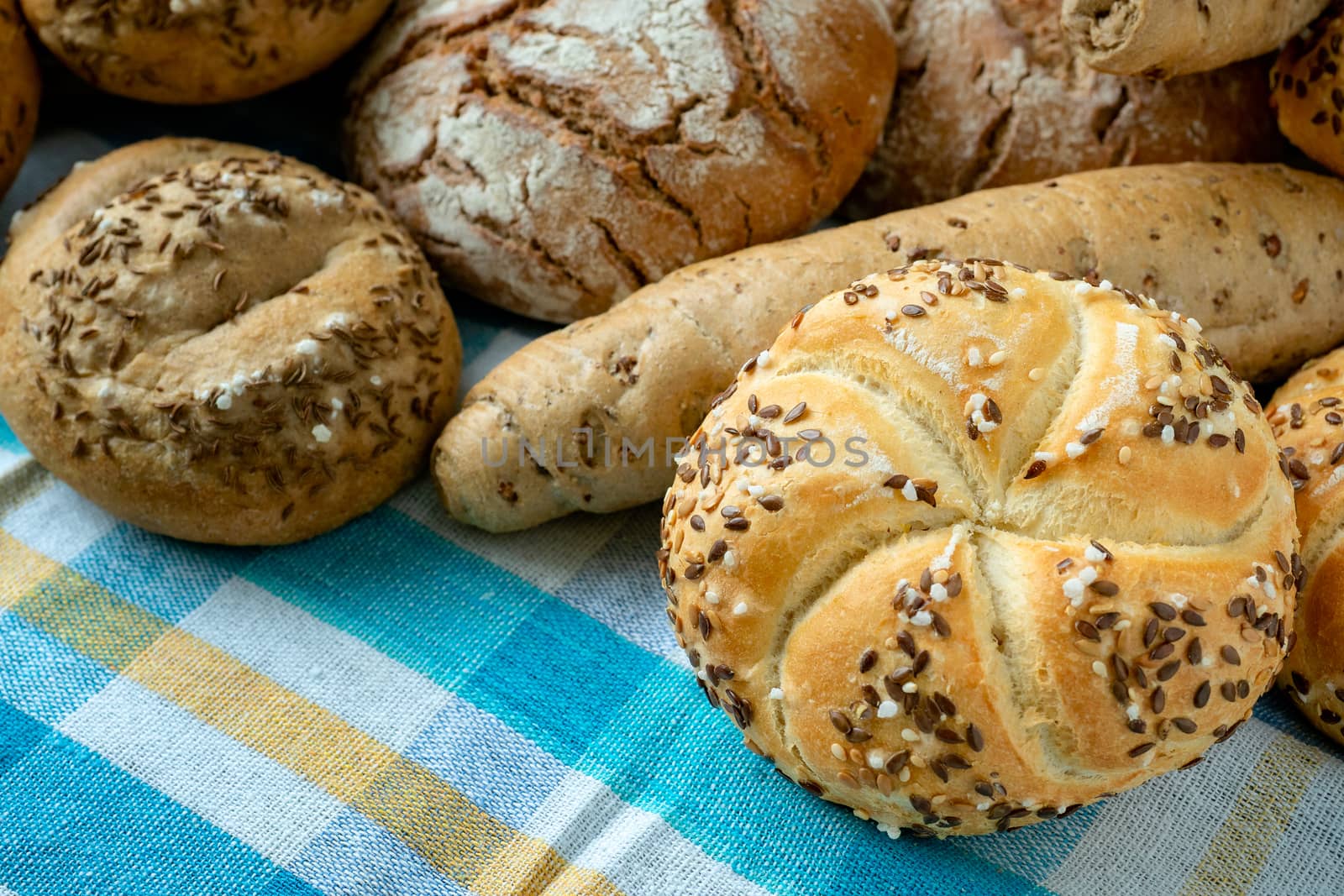 Heap of various bread rolls sprinkled with salt, caraway and sesame. Fresh rustic bread from leavened dough. Assortment of freshly of bakery products