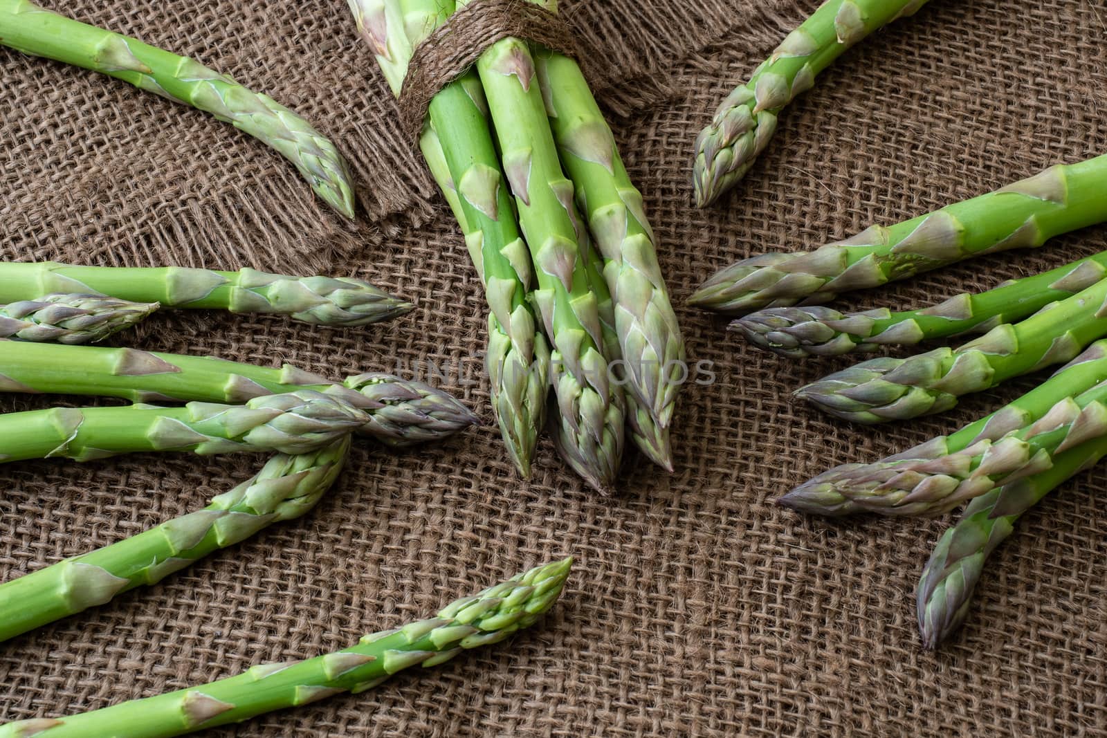 Raw garden asparagus stems. Fresh green spring vegetables on wooden background. (Asparagus officinalis).