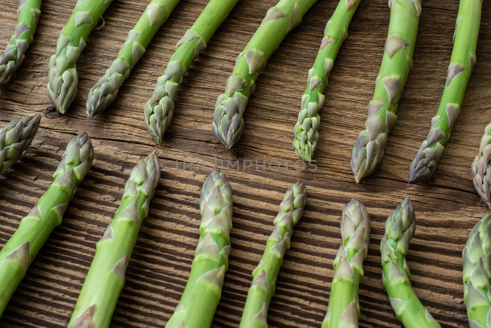Raw garden asparagus stems. Fresh green spring vegetables on wooden background. (Asparagus officinalis).