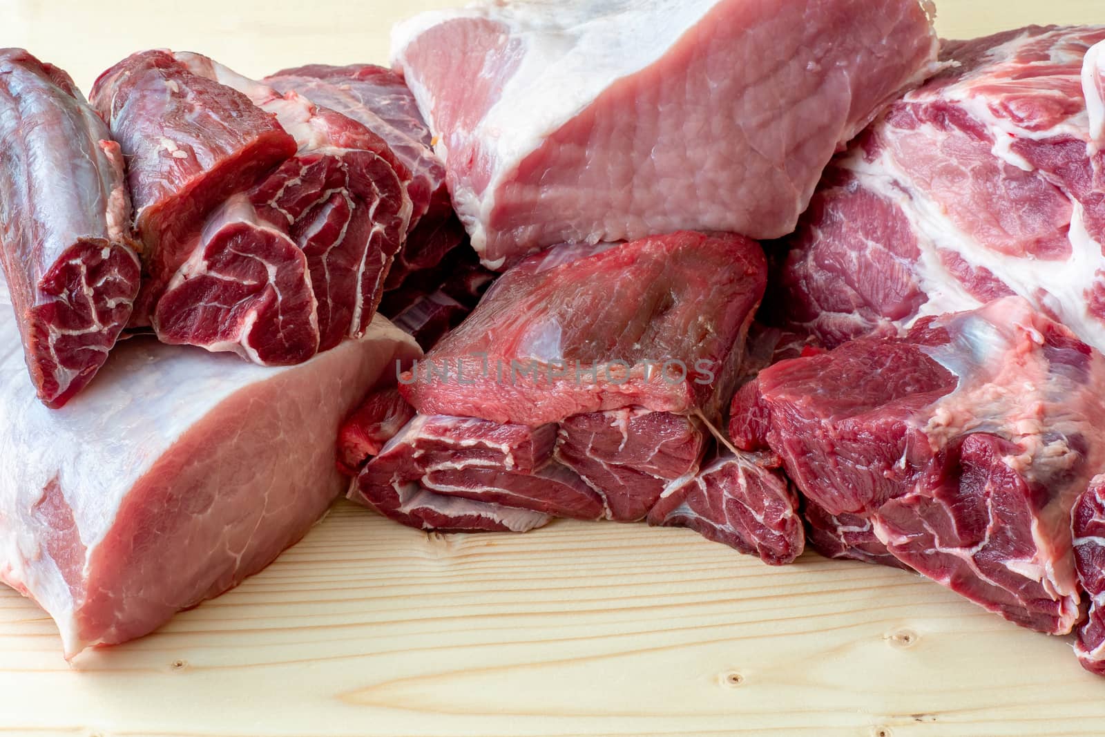 Different types of raw pork meat and beef. Raw meat on wooden table.