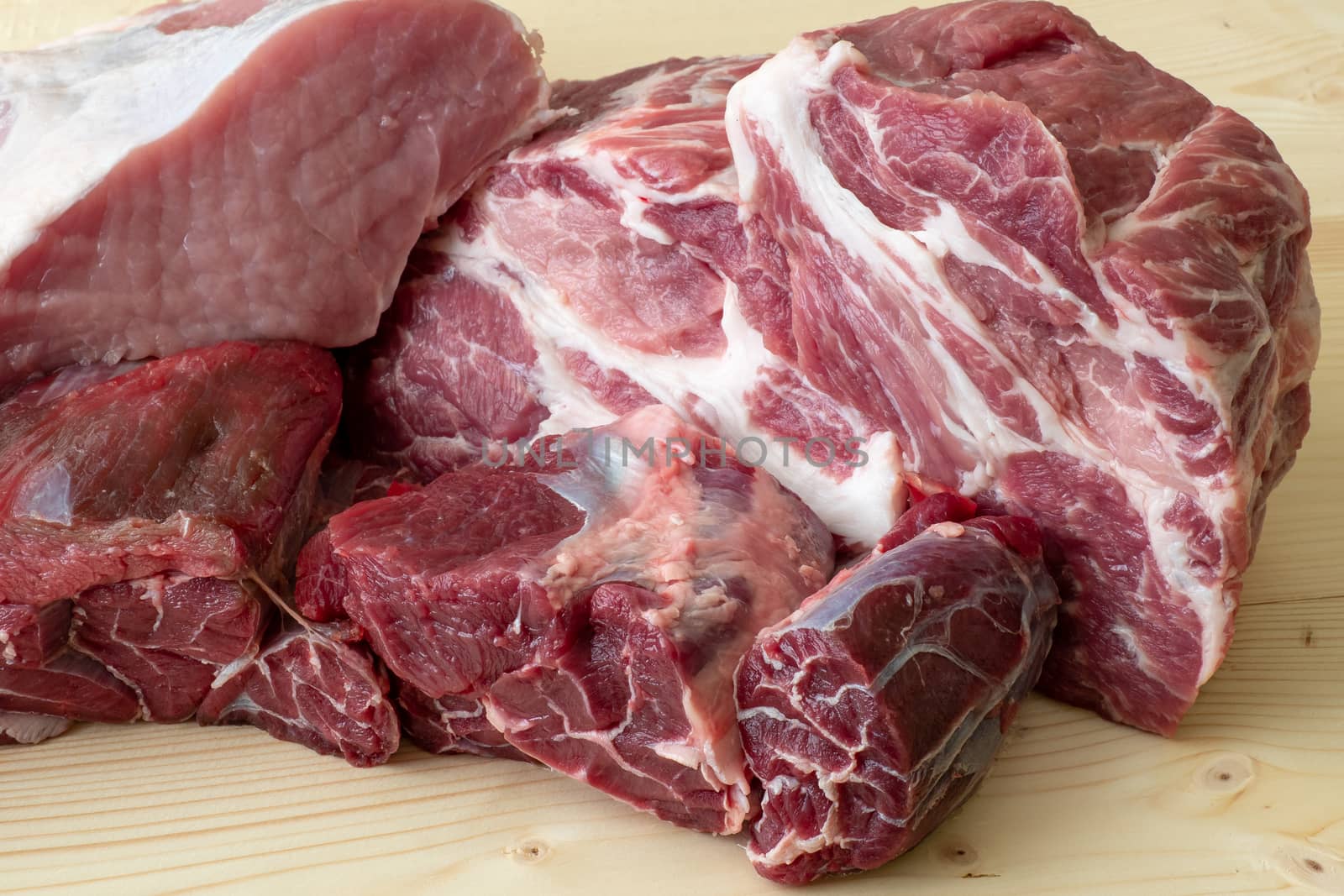 Different types of raw pork meat and beef. Raw meat on wooden table.