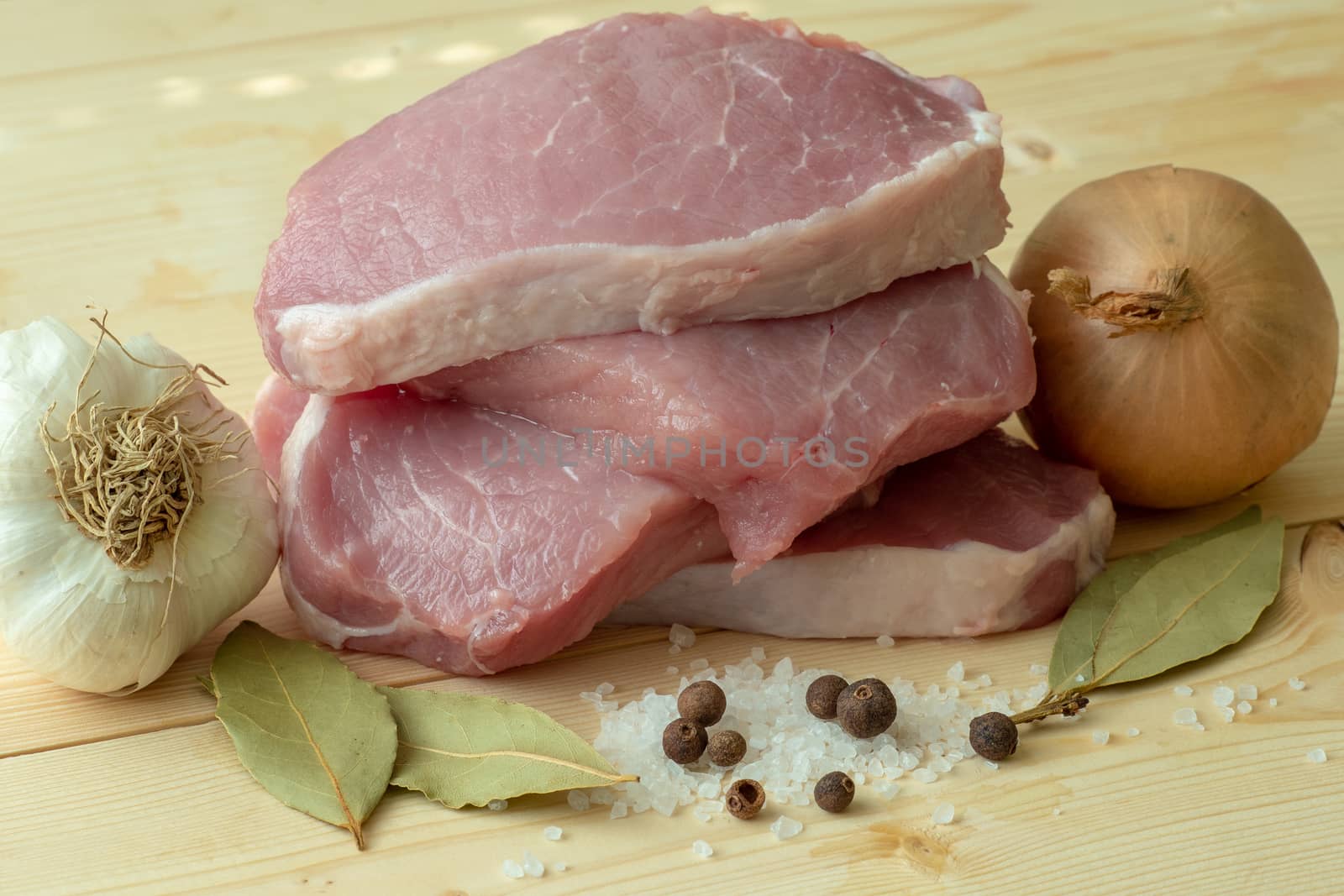 Fresh pork with ingredients for cooking on wooden board