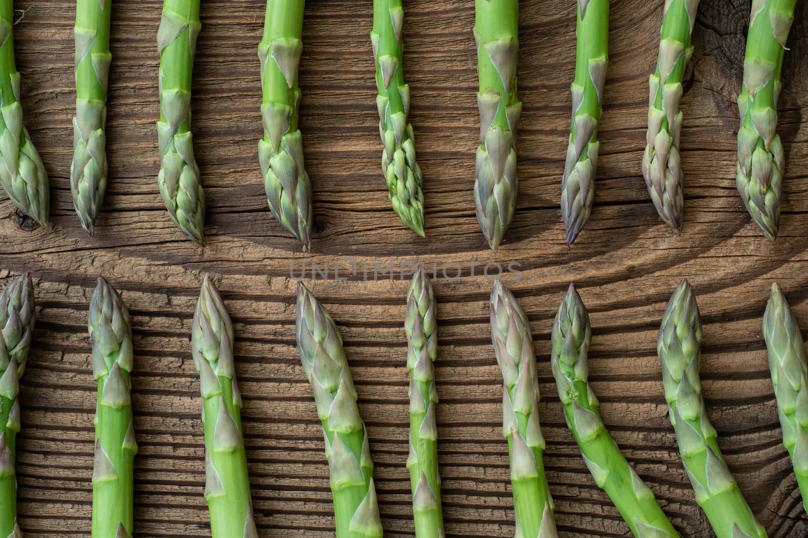 Raw garden asparagus stems. Fresh green spring vegetables on wooden background. (Asparagus officinalis).