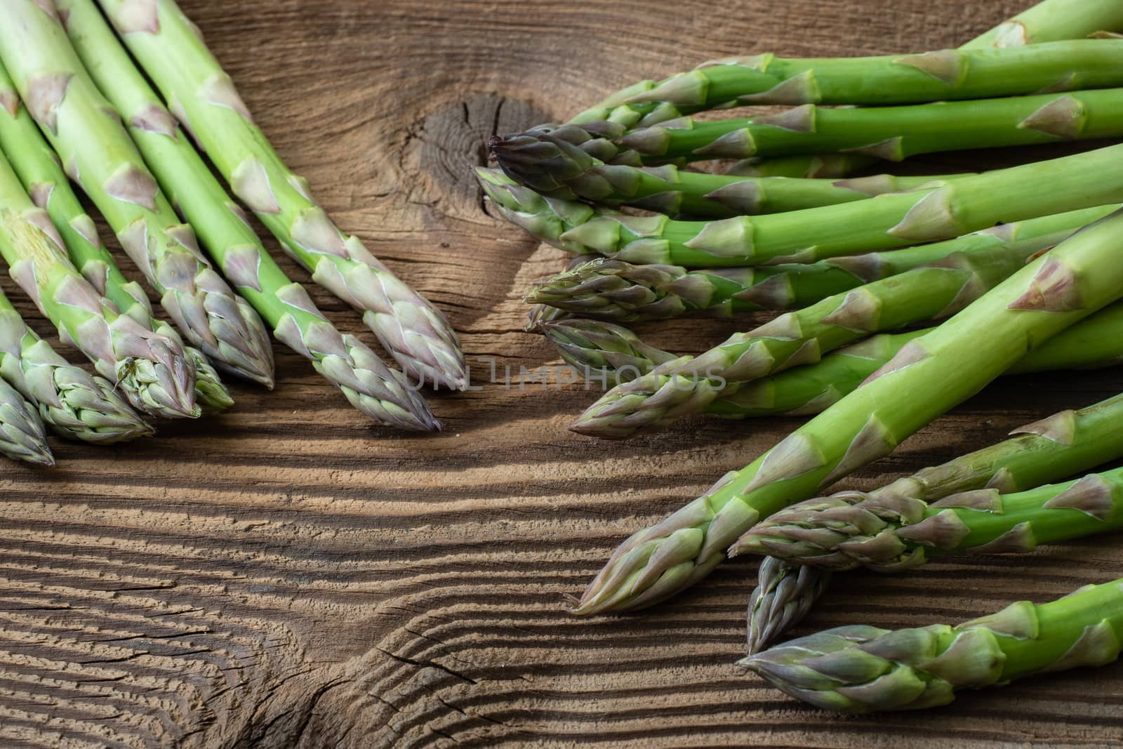 Raw garden asparagus stems. Fresh green spring vegetables on wooden background. (Asparagus officinalis).