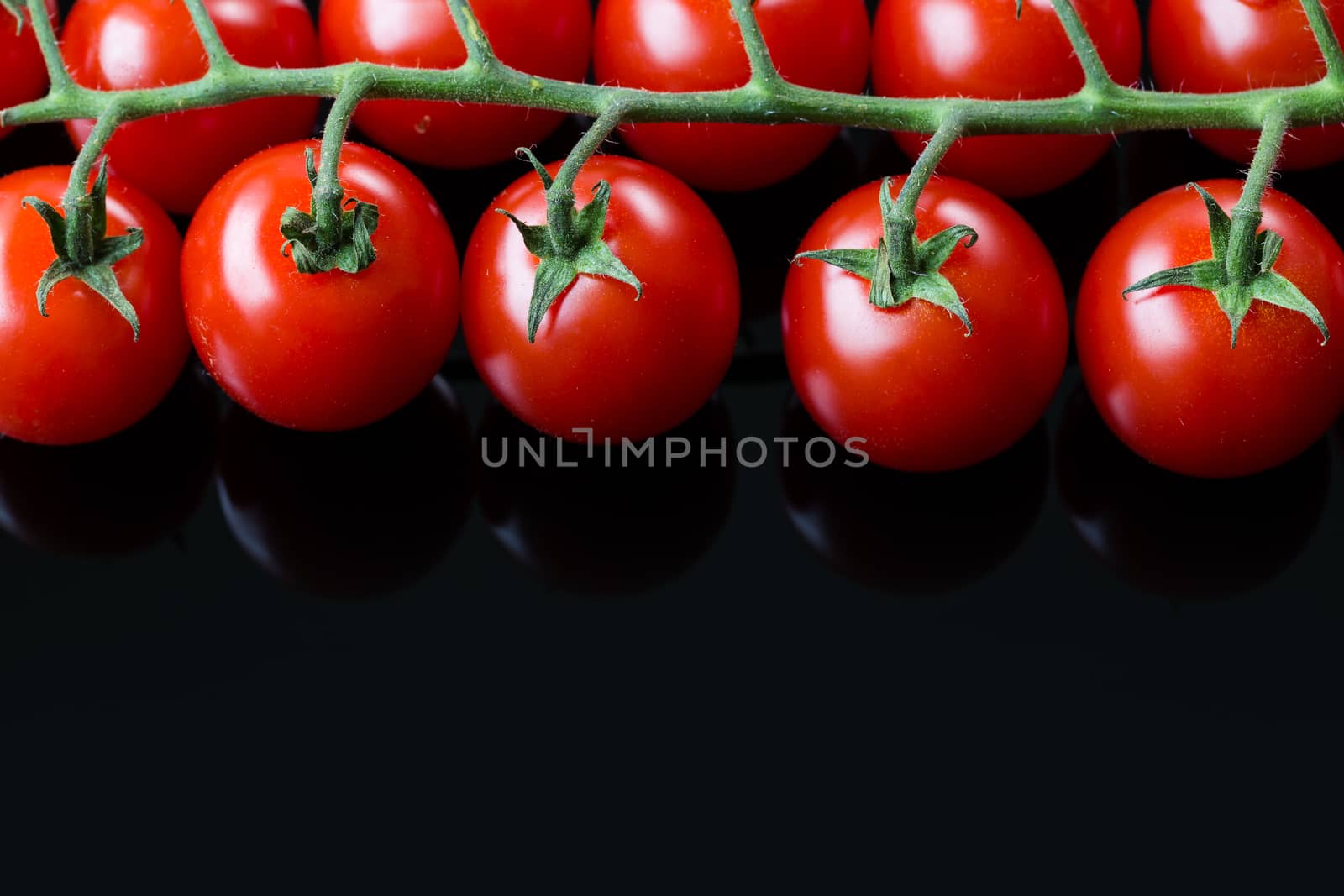 Fresh cherry tomatoes on a black background. Bunch of fresh cherry tomato on a black background