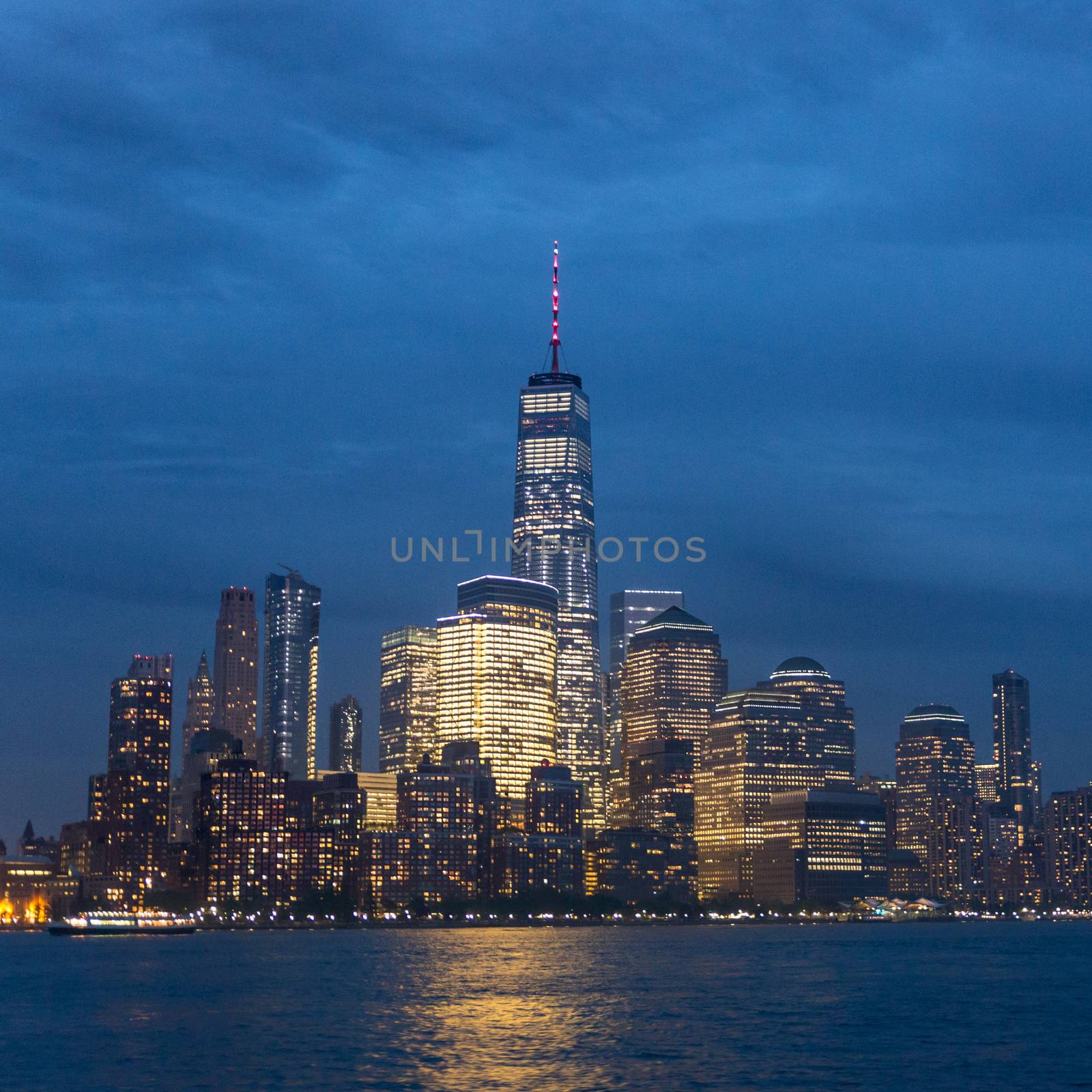 Panoramic view of Lower Manhattan from Ellis Island at cloudy dusk, New York City.