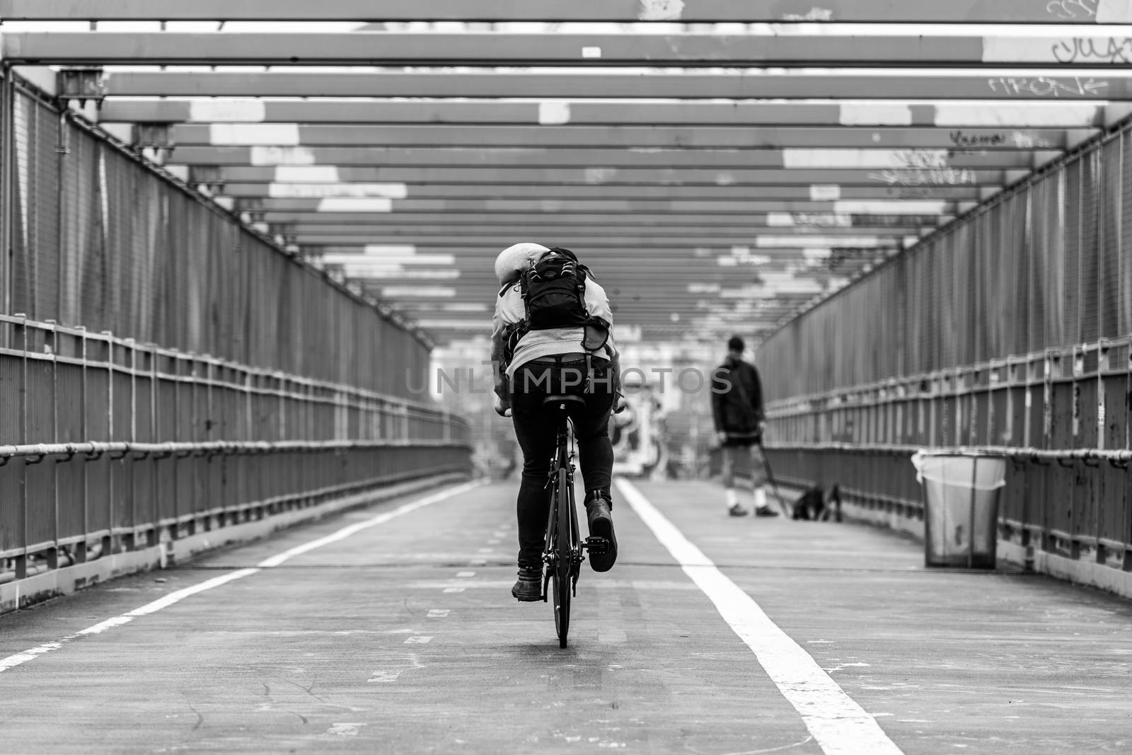 Man riding his bike in the cycling lane on Williamsburg Bridge, Brooklyn, New York City, USA. Black and white image.