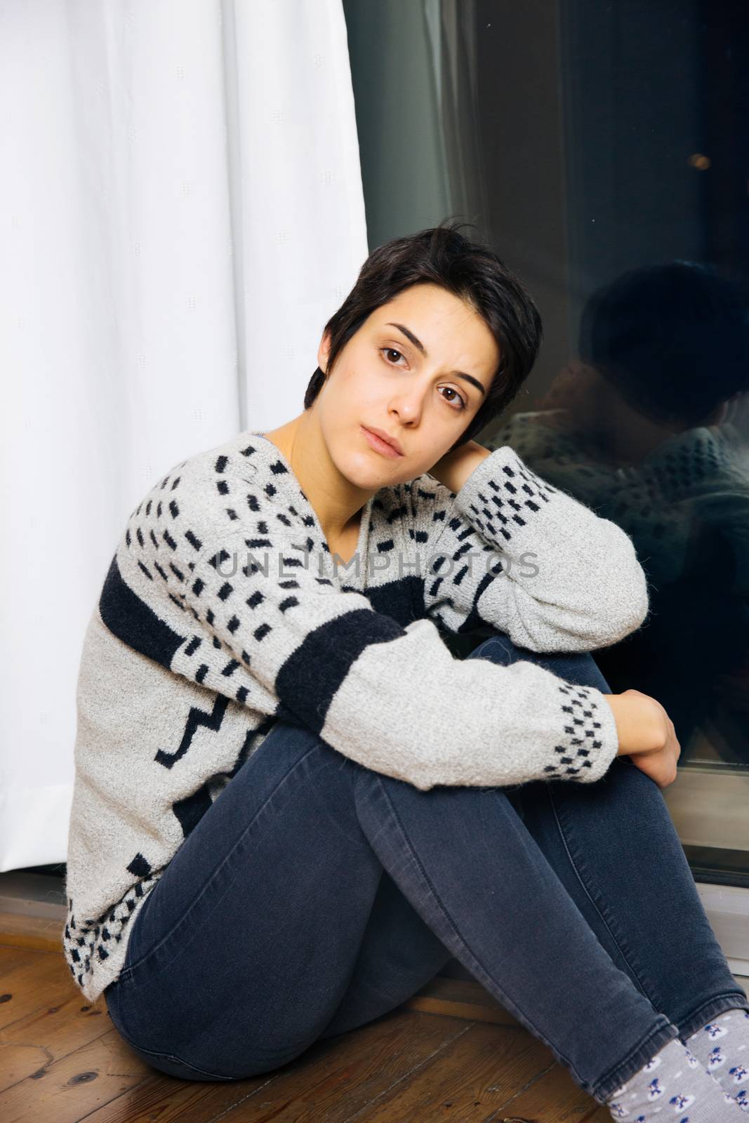 Sad woman sitting on the floor in corner of room, portrait of a sad teenage girl looking thoughtful about troubles. Lonely Depressed woman.