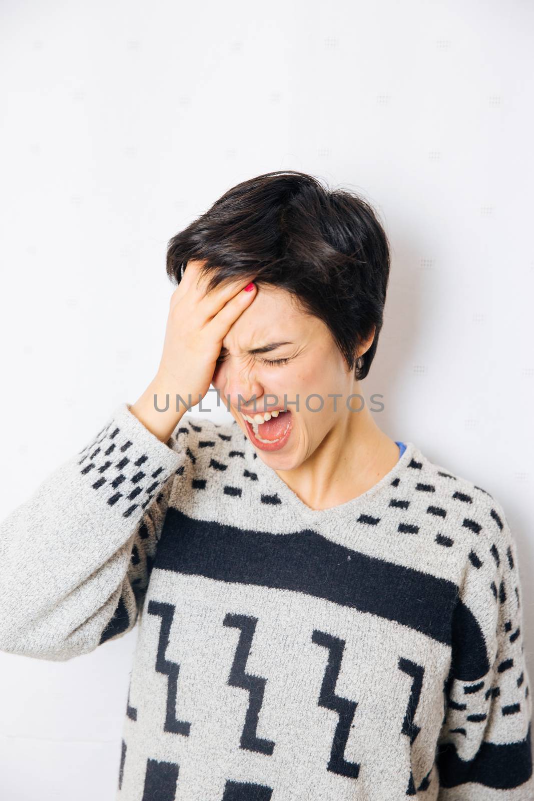 Portrait of young upset and stressed woman standing near the wall with headache and lot of problems.