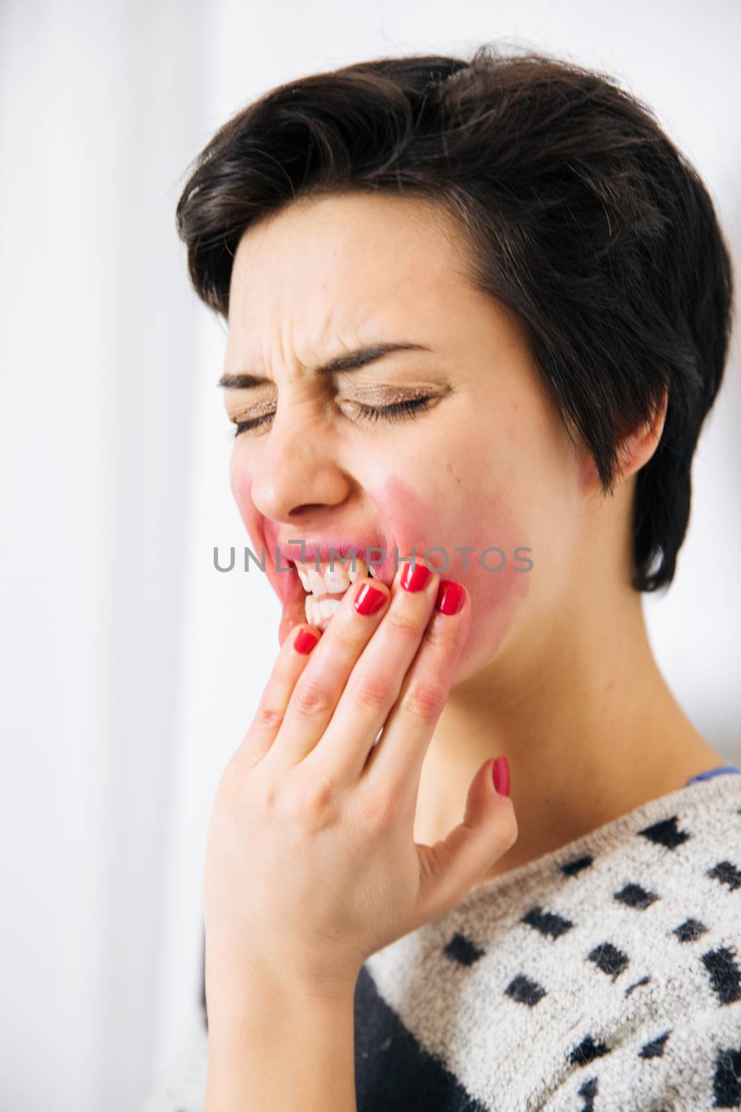 Portrait of young upset and stressed woman standing near the wall with toothache and lot of problems.