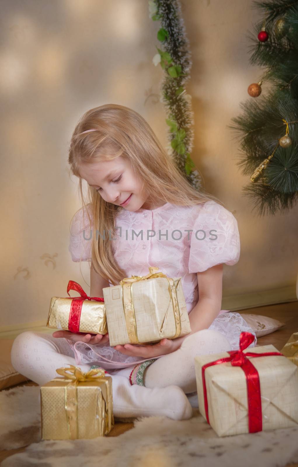 Cute girl among Christmas gifts dreaming