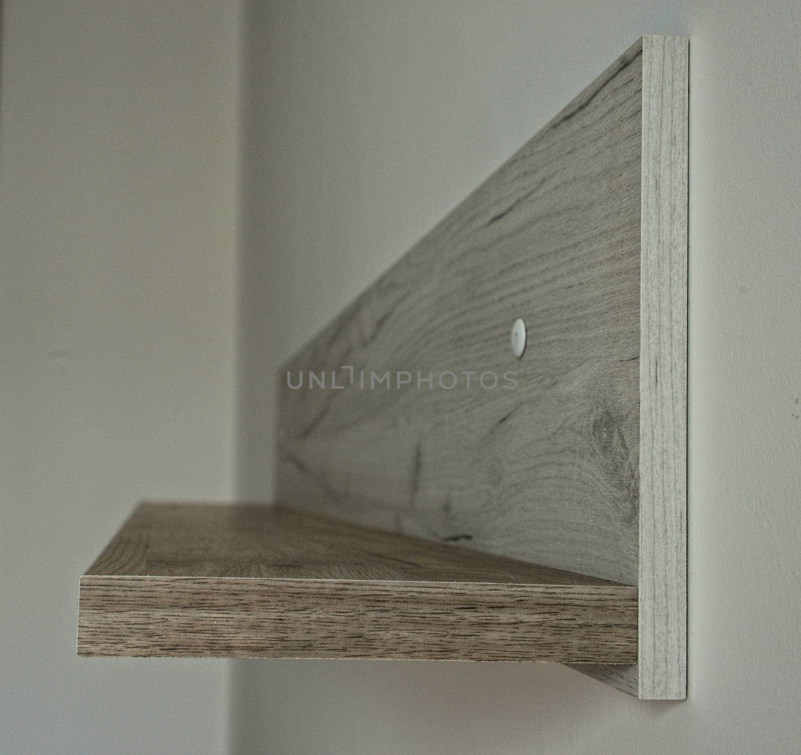 Empty gray wooden shelf on white wall, side view by sheriffkule