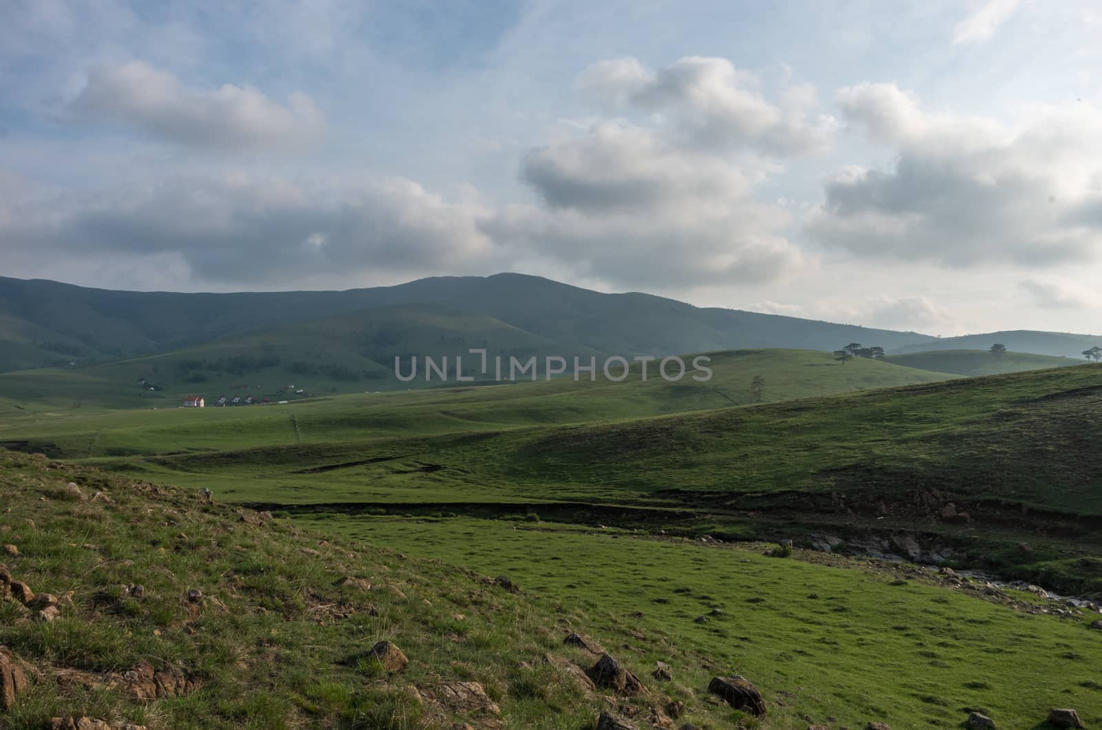 Spring landscape in sunset with clouds, hills and meadow. Zlatibor mountain area, Serbia