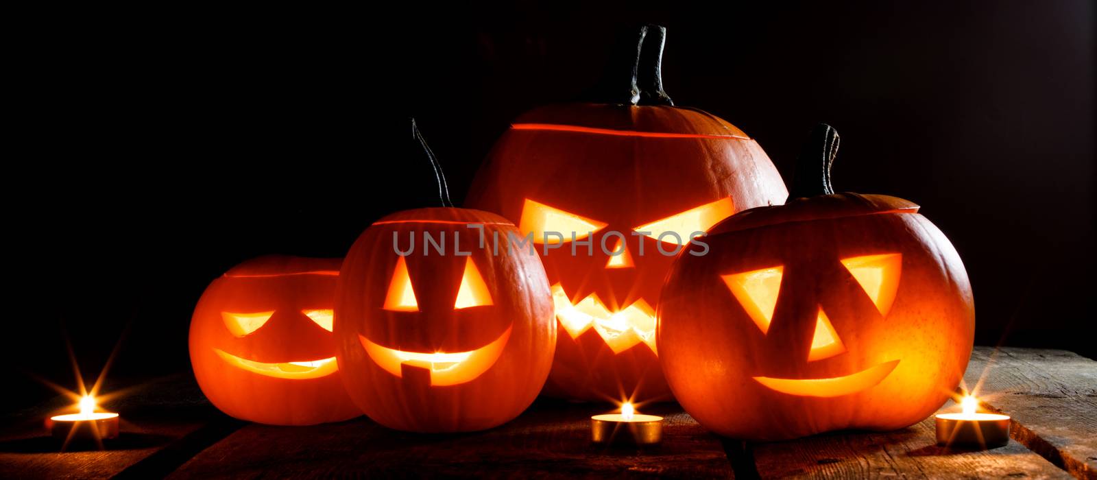 Halloween pumpkin heads jack o lantern and candles on wooden background