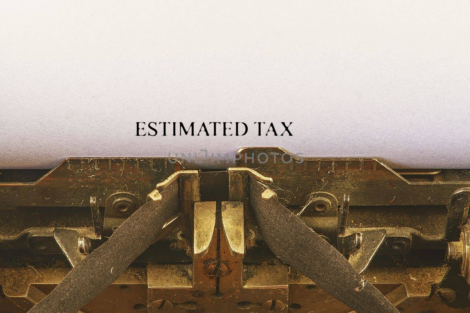 Closeup on vintage typewriter. Front focus on letters making ESTIMATED TAX text. Business concept image with retro office tool.