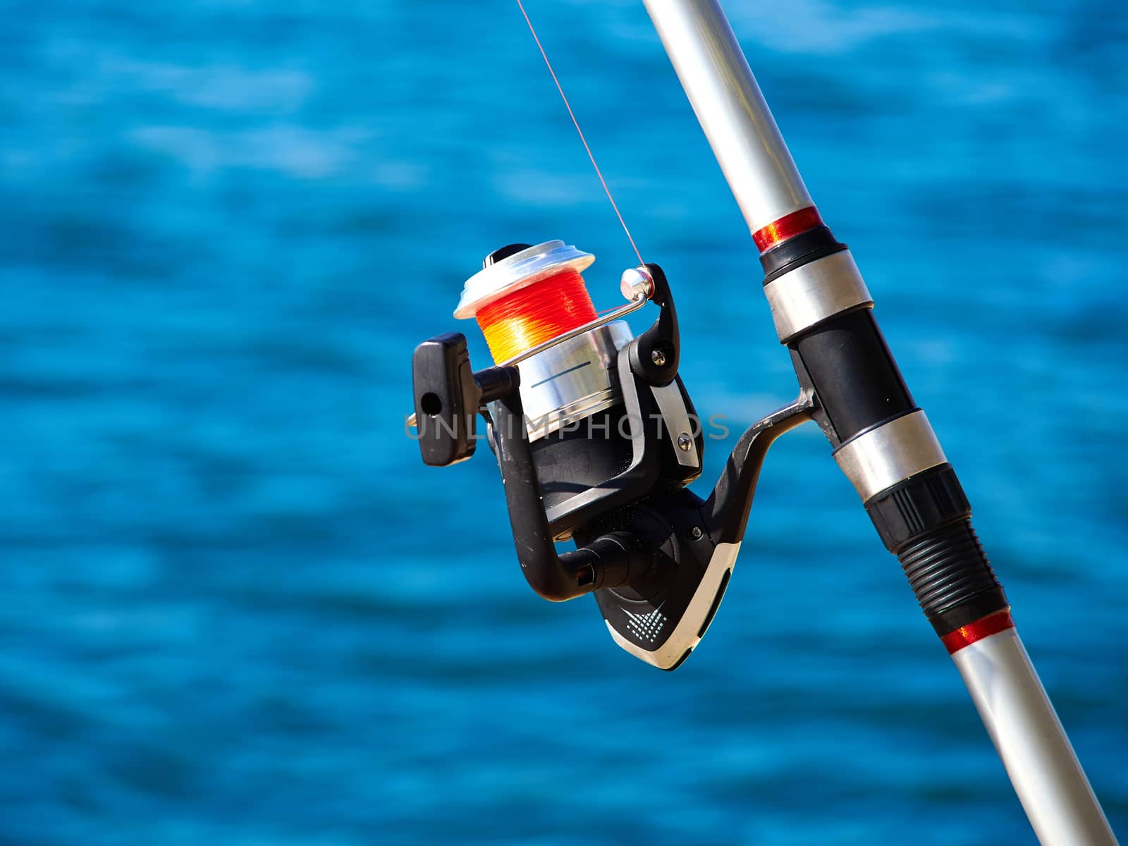 Fishing rod with a spinning reel with sea beach ocean background
