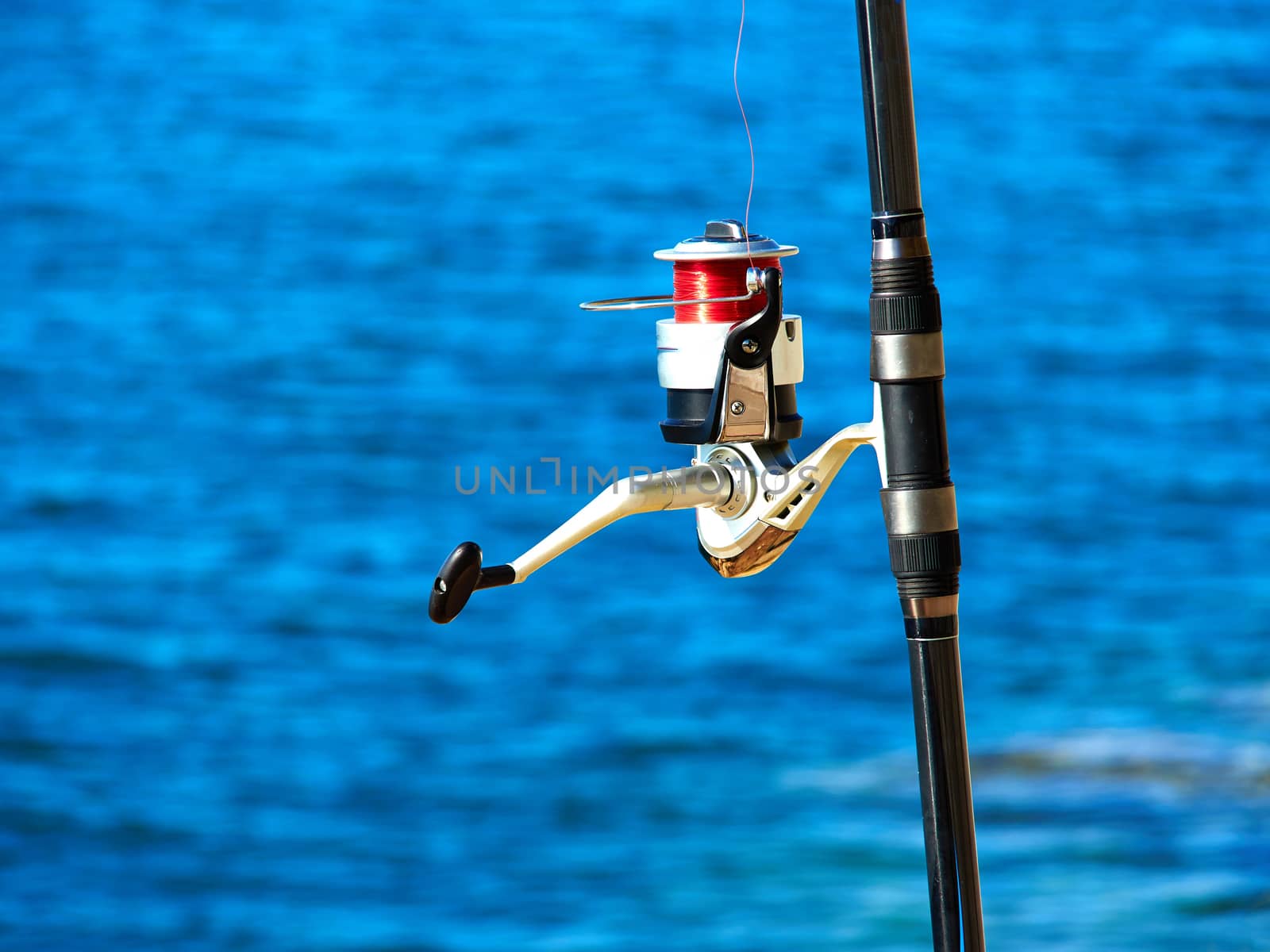 Fishing rod with a spinning reel with sea beach ocean background   