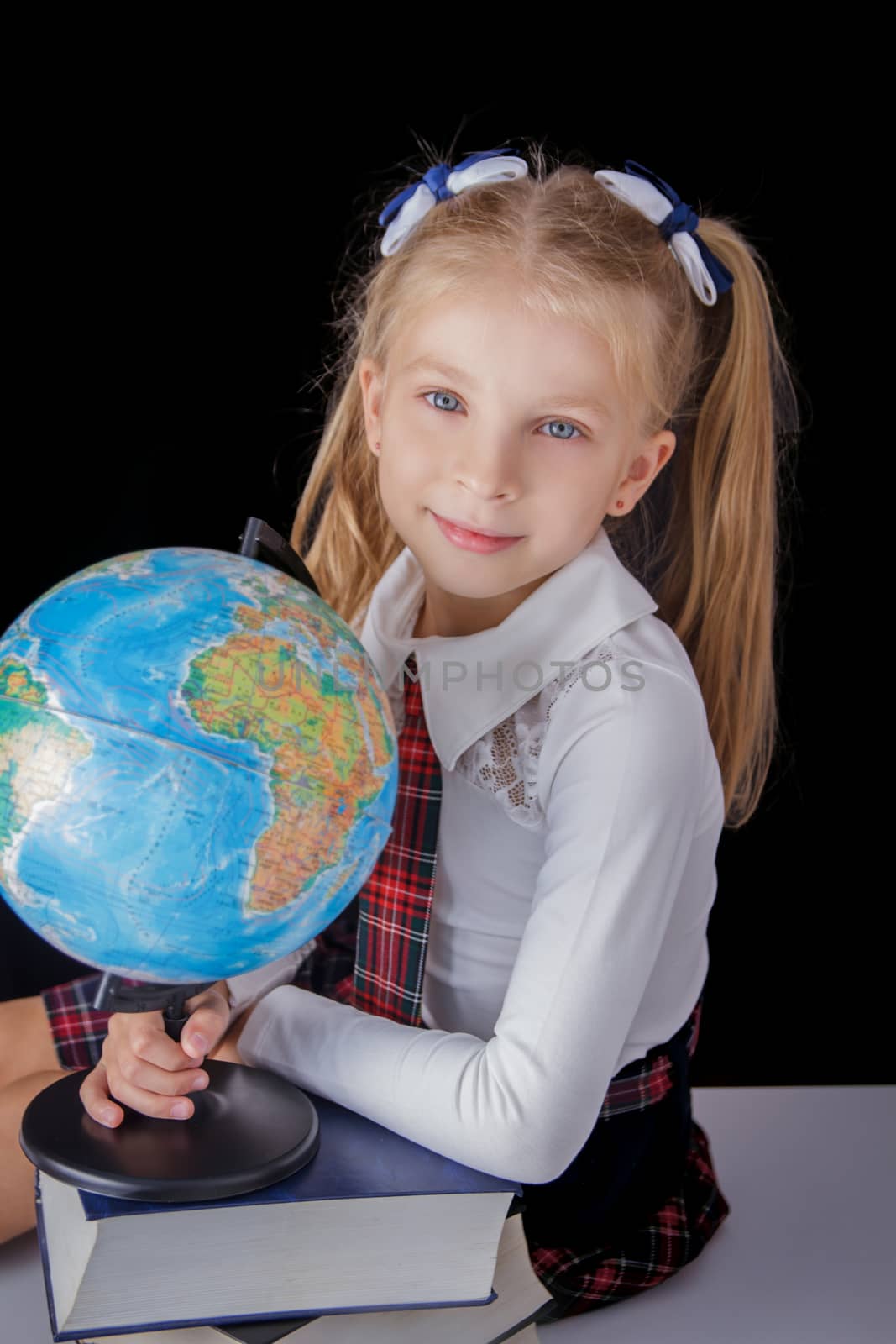 Schoolgirl with globe sitting on black background, education and school concept