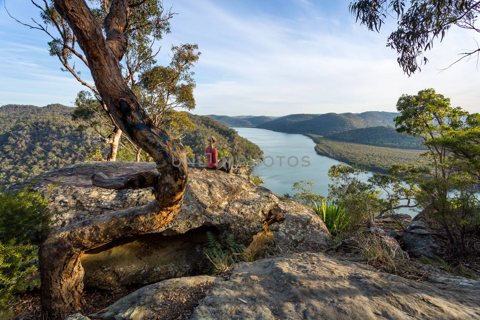 Woman relaxing on a rocky outlook with river views in Australian bushland by lovleah