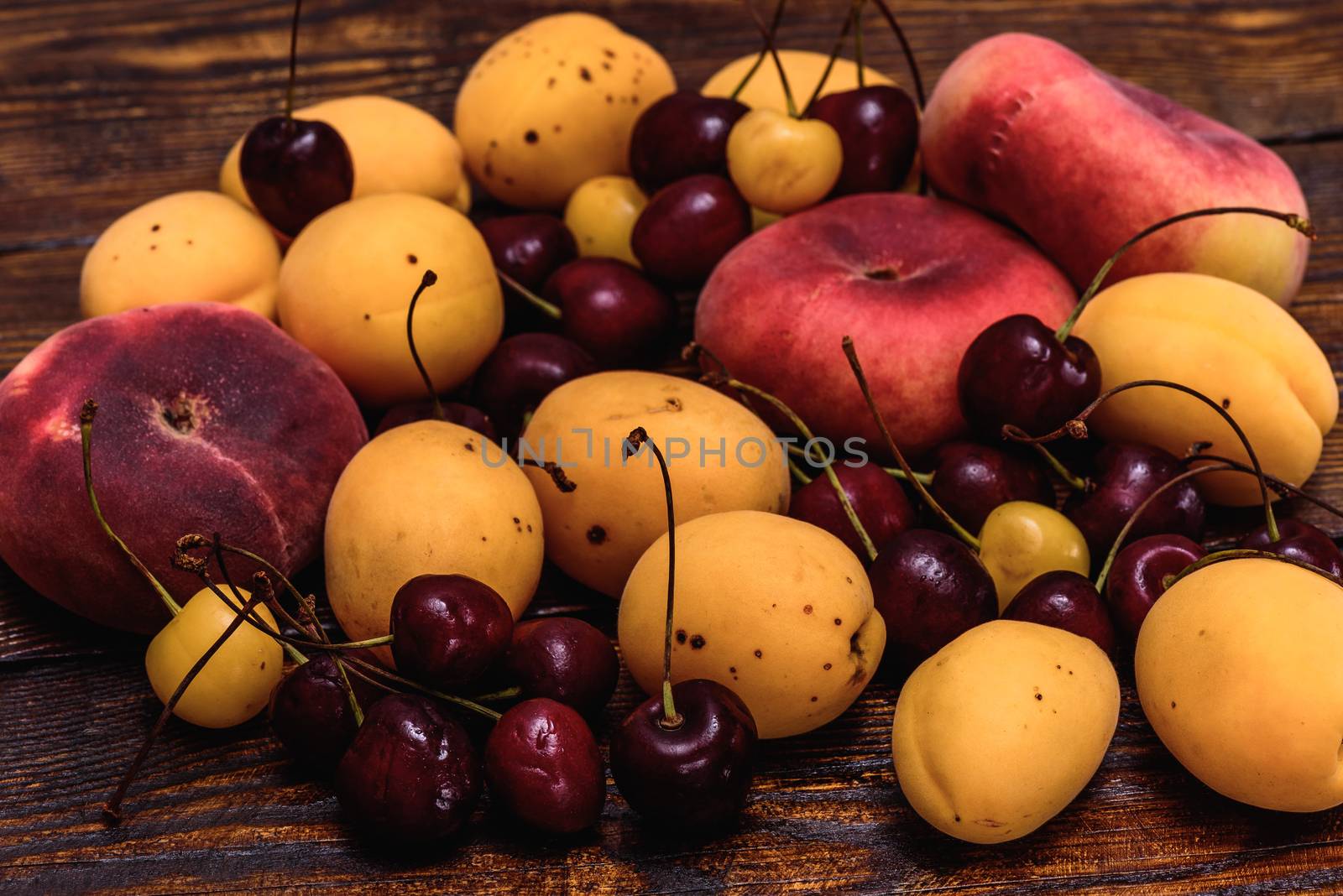 Fruits fig peaches, apricot and cherry on dark wooden table