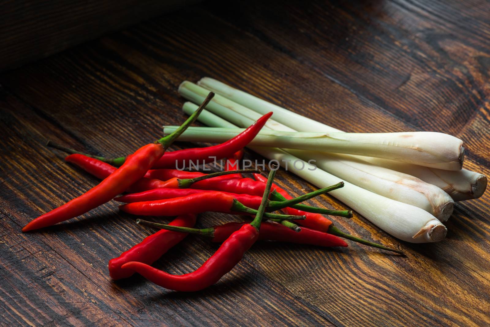 Pile of thai Bird's Eye Chilis with lemongrass on a old wooden table by Seva_blsv