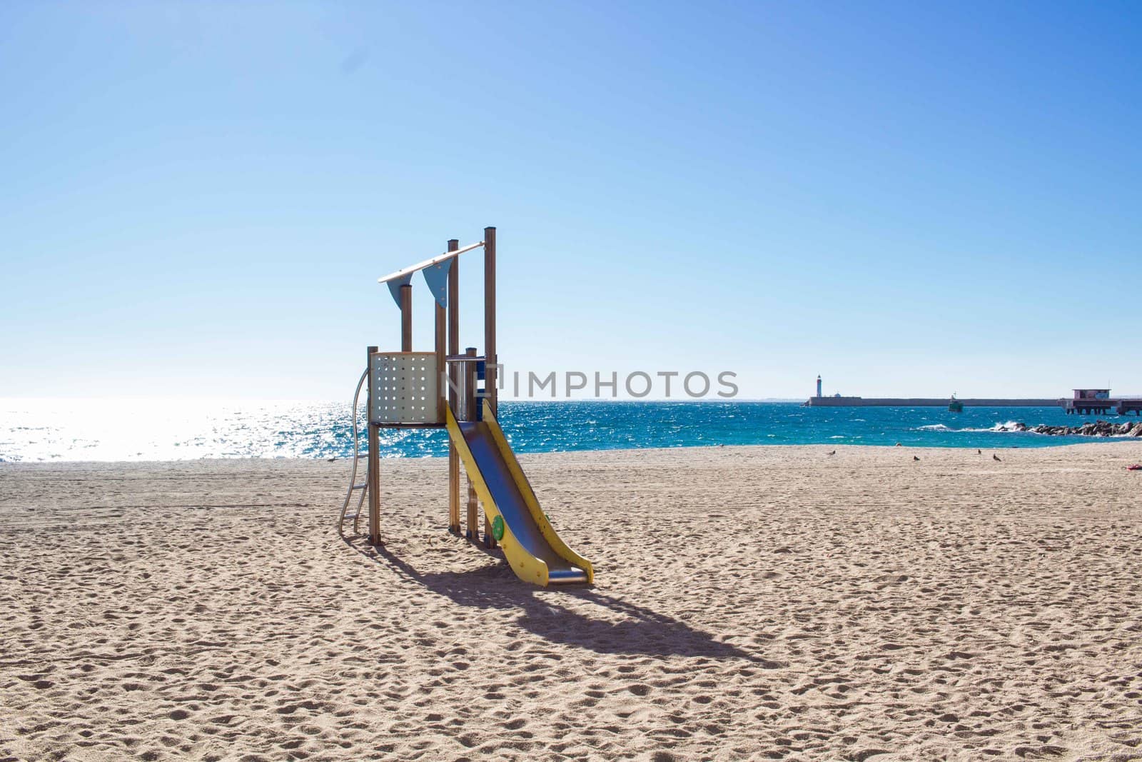 Children slide on sandy coastal beach seafront of mediterranean city