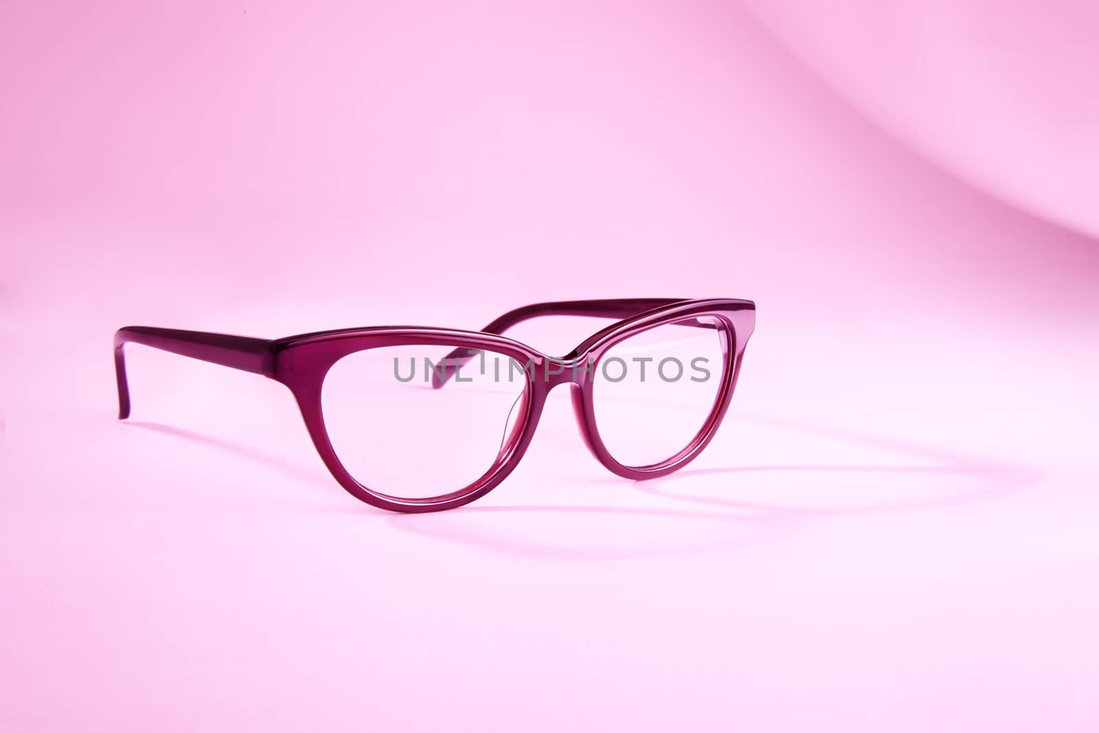Advertising studio shot of pink glasses with long shadow at pink background.