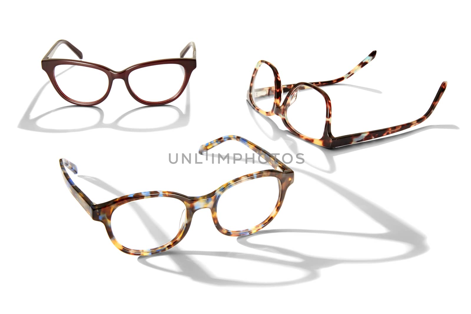 Studio photo of three pairs of glasses with long shadow isolated on white background.