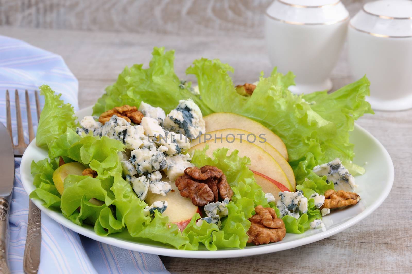 A light lettuce salad with pear slices, gorgonzola pieces and walnut seasoned with olive oil