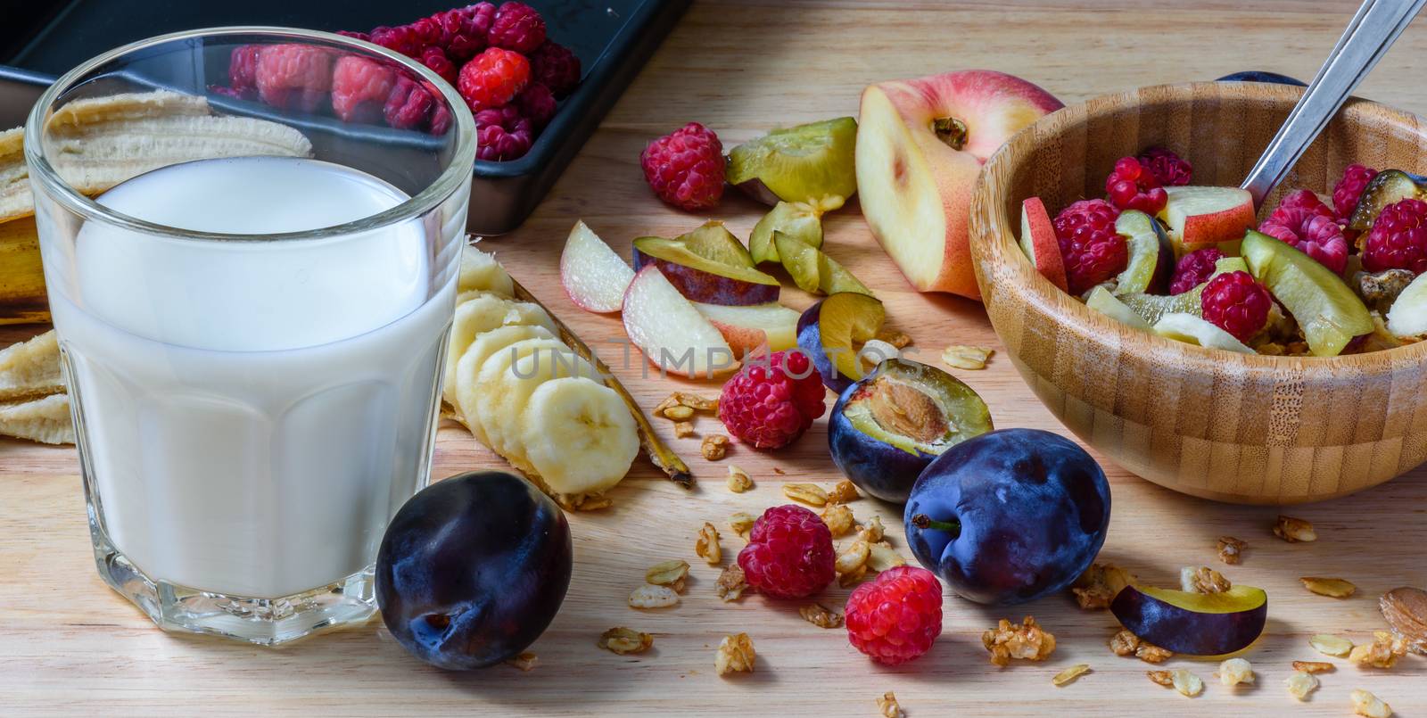 Bowl of muesli with berries, fruits and milk - good and healthy breakfast. Scattered ingredients and slices of fruits